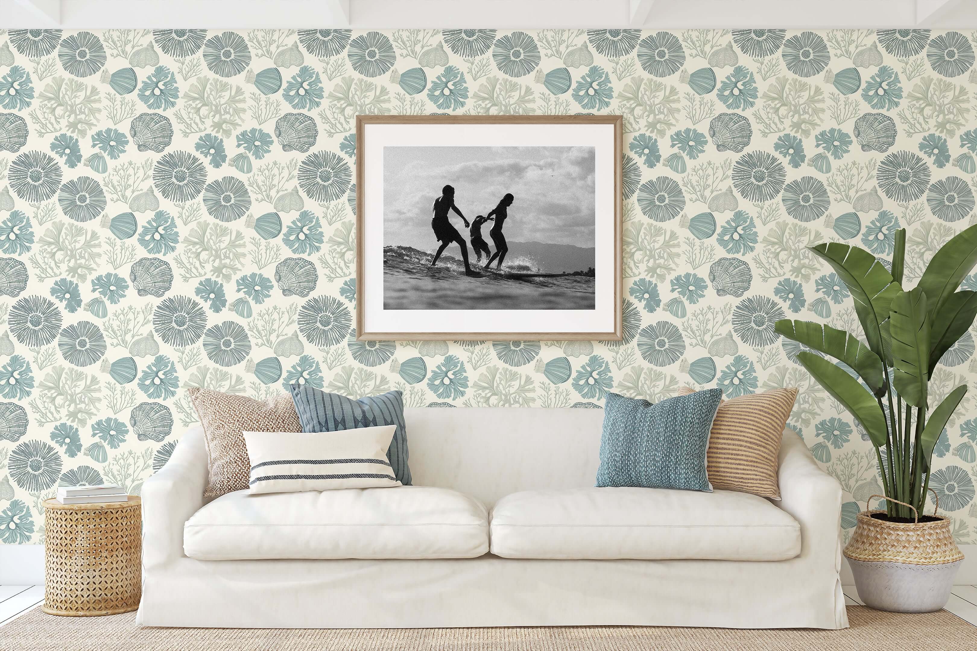 Beach-inspired room with coastal "Shoreline Charm" wallpaper, featuring sea anemones, coral, and seashell patterns, behind a white sofa.