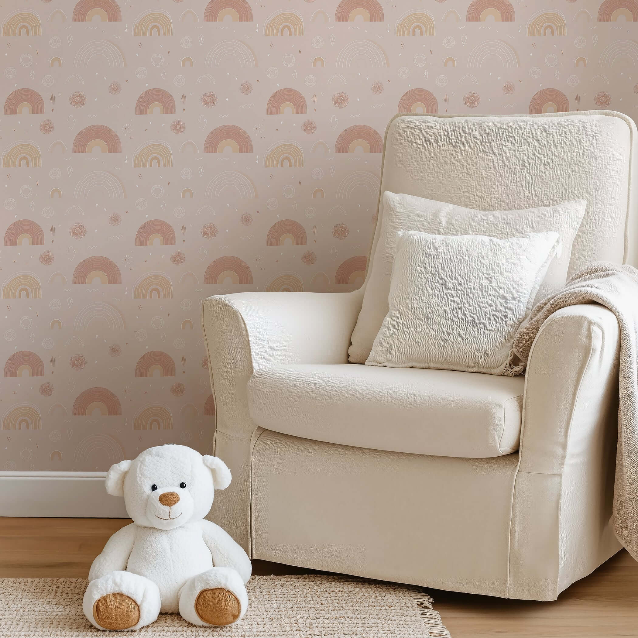 Soft beige wallpaper with hand-drawn pink rainbows in a cozy nursery featuring a teddy bear and cream armchair, perfect for kids' rooms.