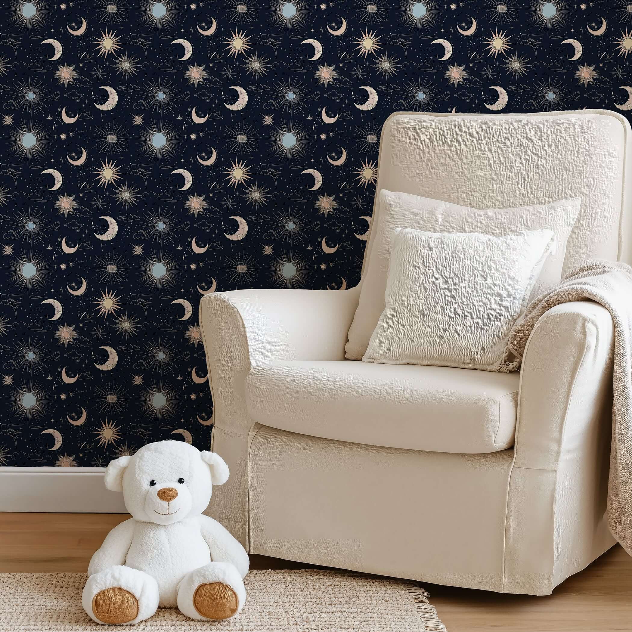 Night Sky Magic Wallpaper with stars, moons, and suns on a midnight blue sky in a nursery with a cozy chair and teddy.