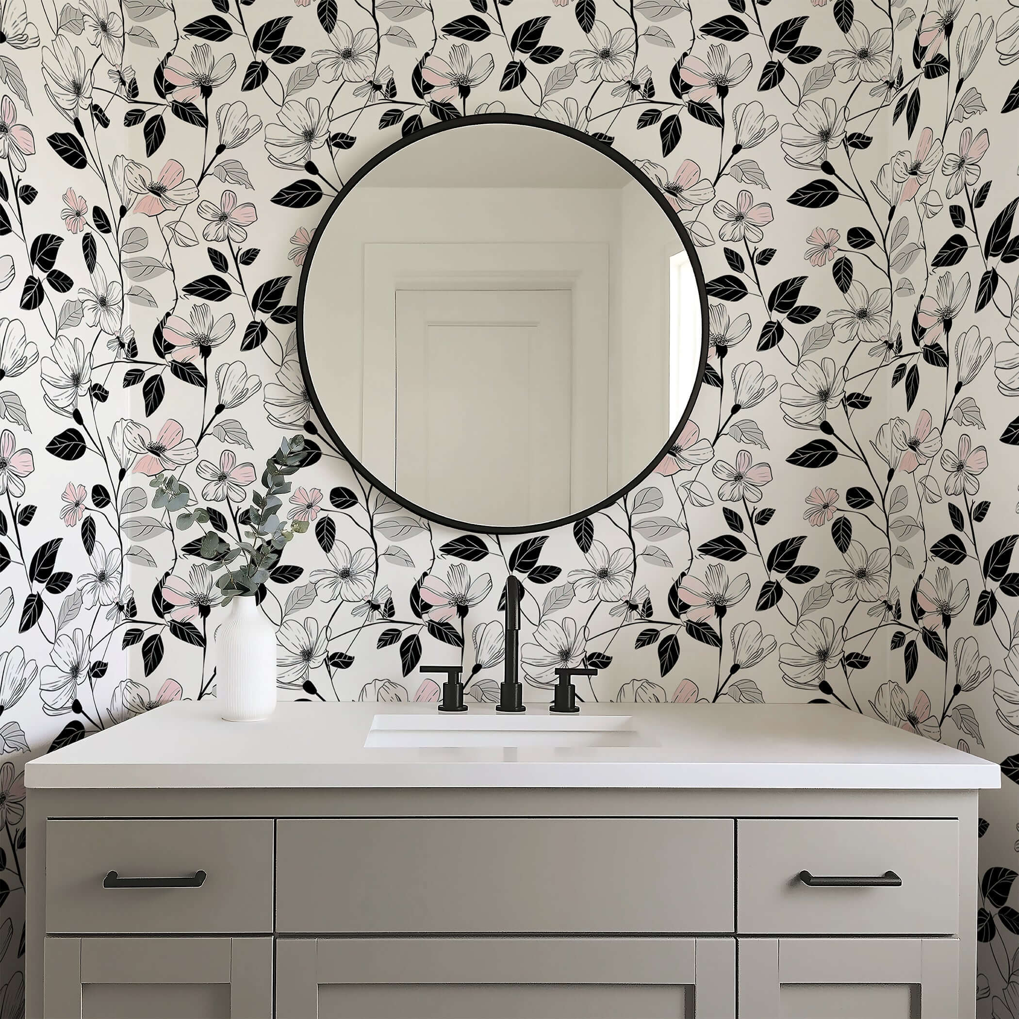 Modern monochrome floral wallpaper with blush flowers and black foliage in a bathroom with a round mirror.