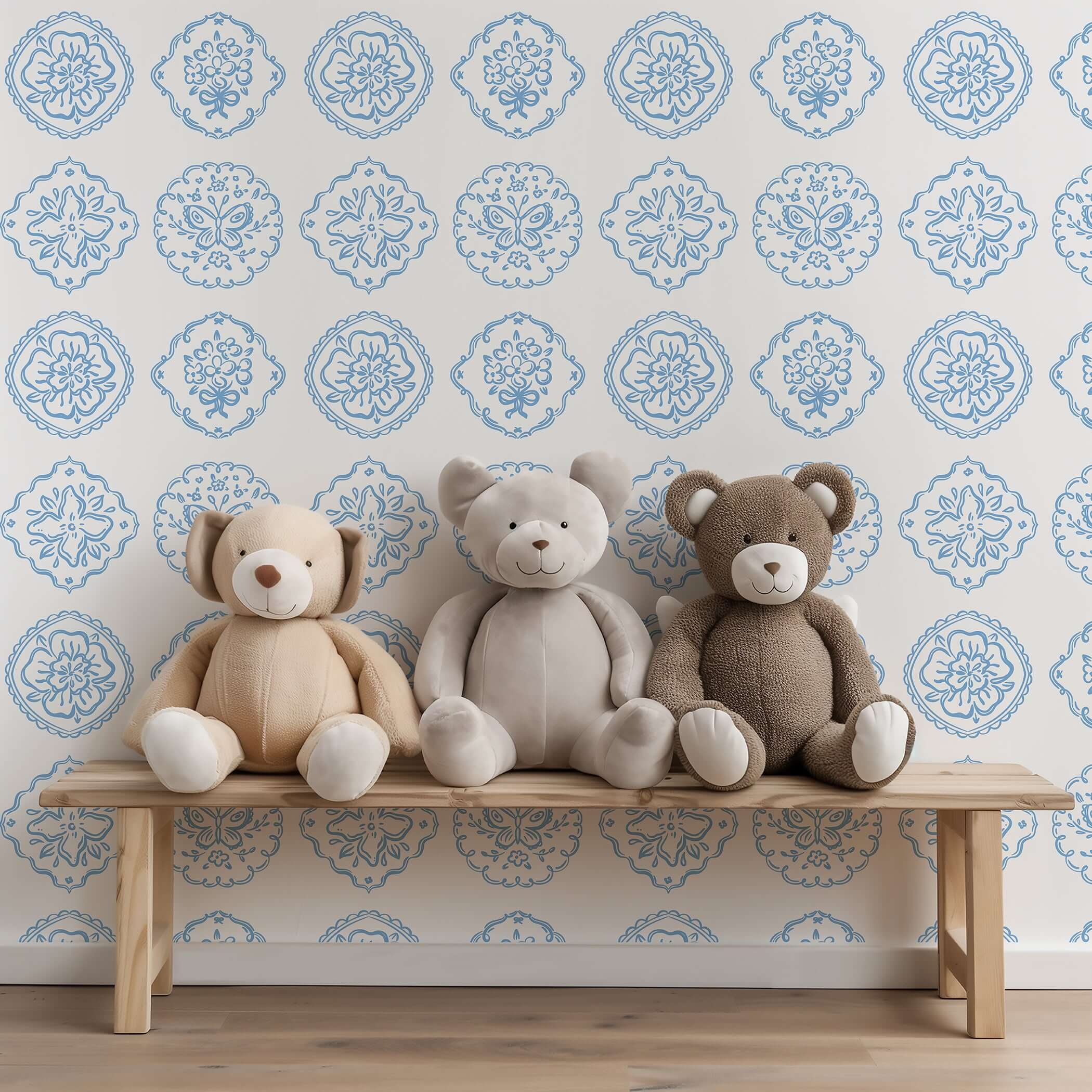 Chateau Garden wallpaper with blue floral medallions displayed behind plush teddy bears on a wooden bench, ideal for a nursery.