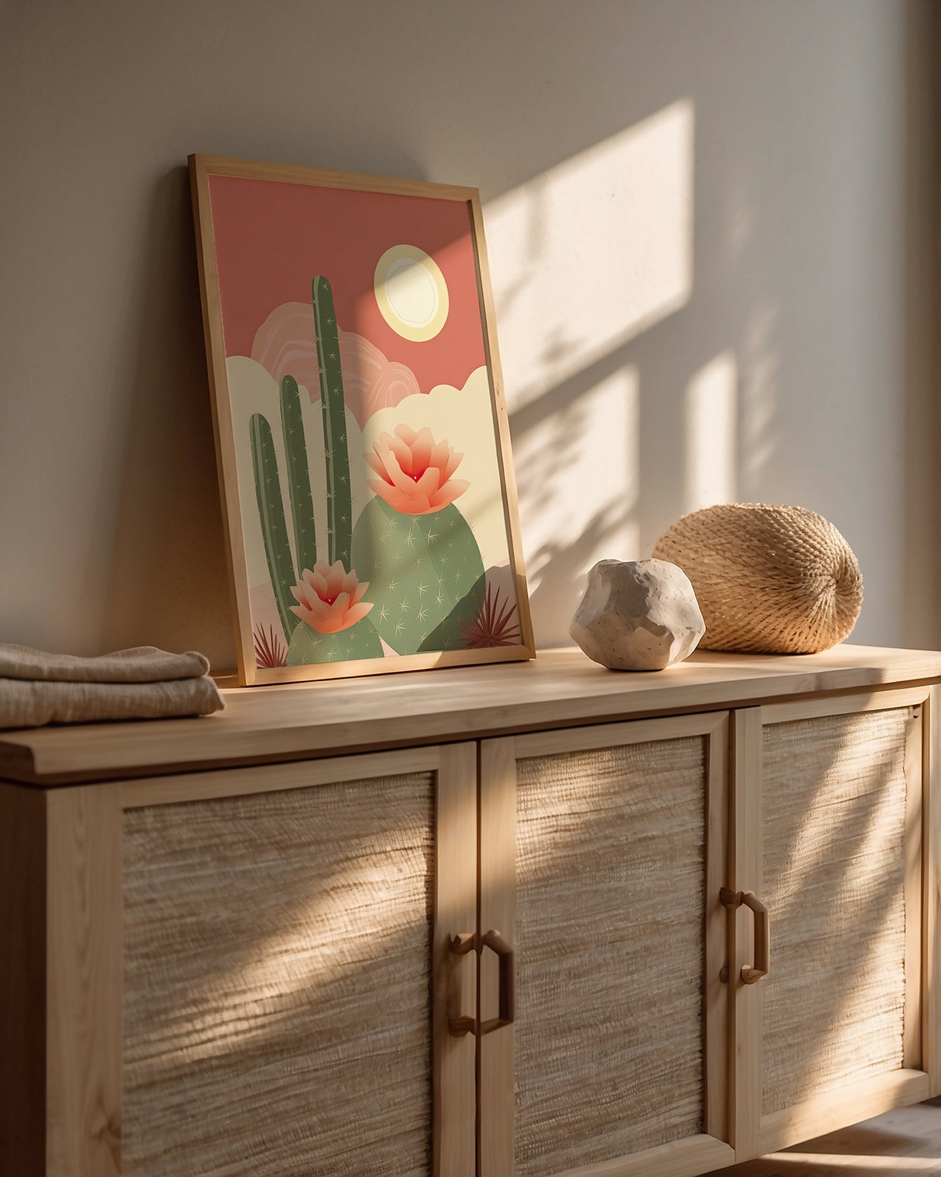 Boho art print featuring cacti and flowers, displayed on a modern cabinet in a softly lit interior.