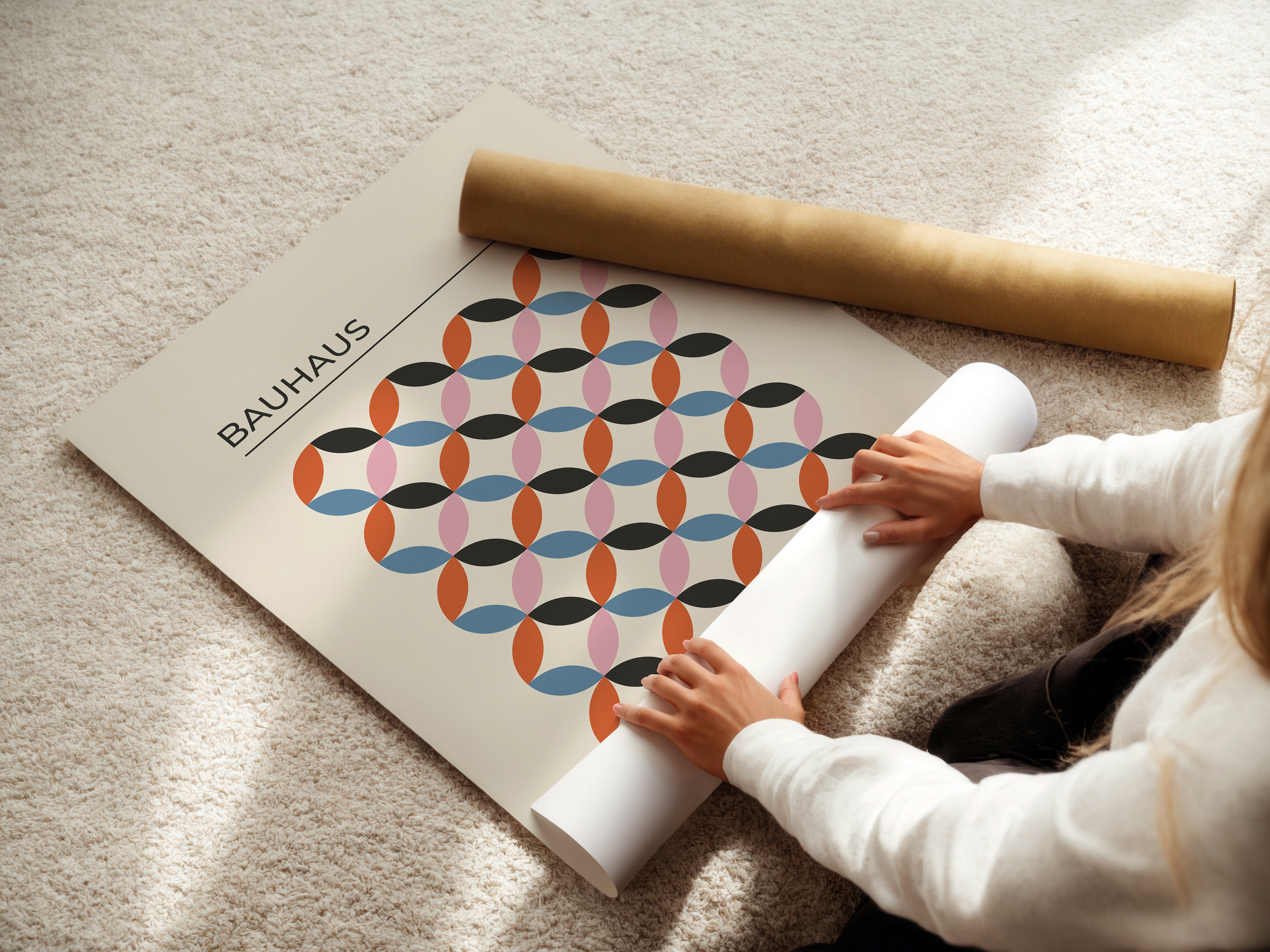Person unrolling a Bauhaus-inspired wall art print featuring geometric patterns and bold colors on a carpet.