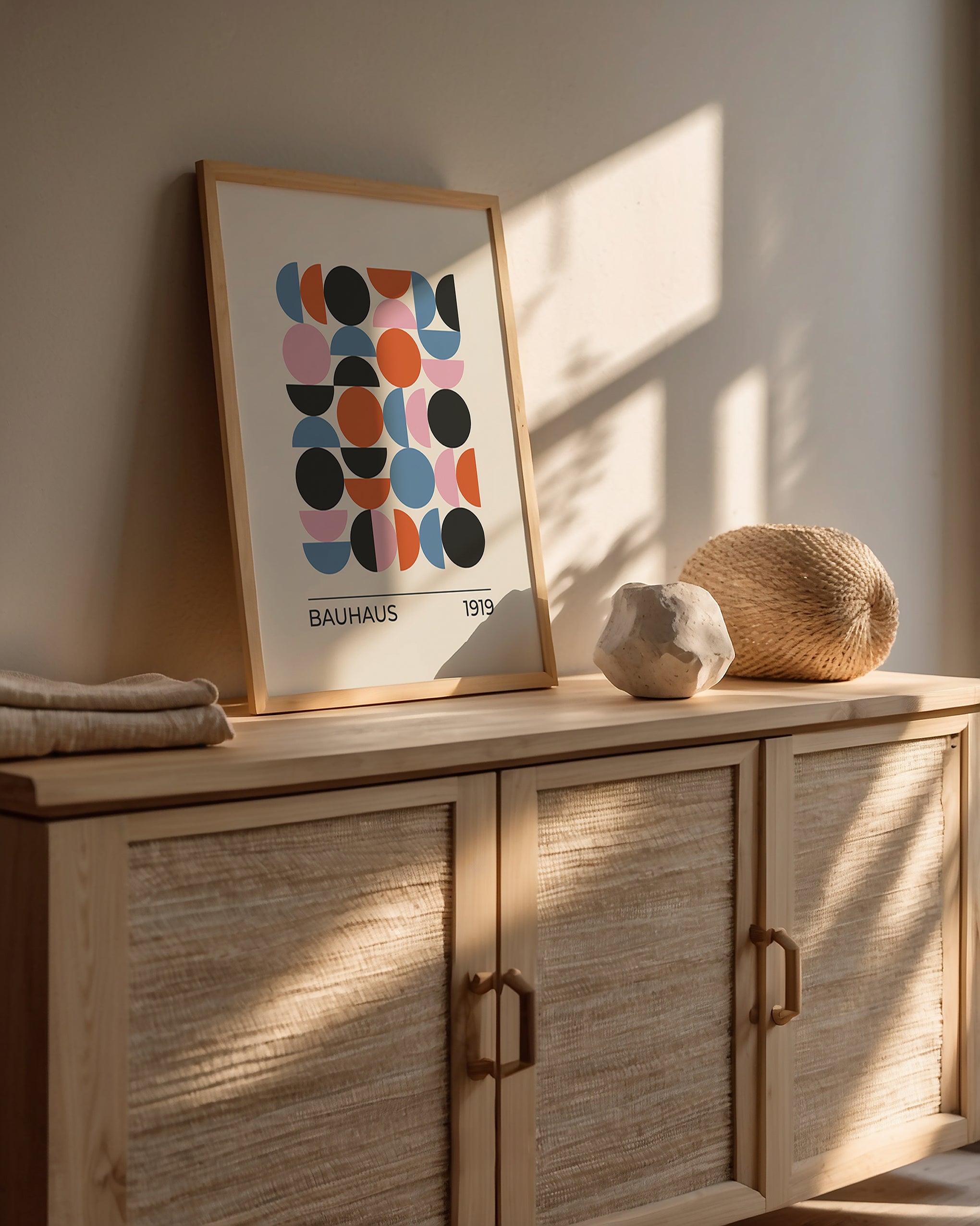 Framed Bauhaus-inspired wall art print on a wooden console with sunlight and decorative elements.