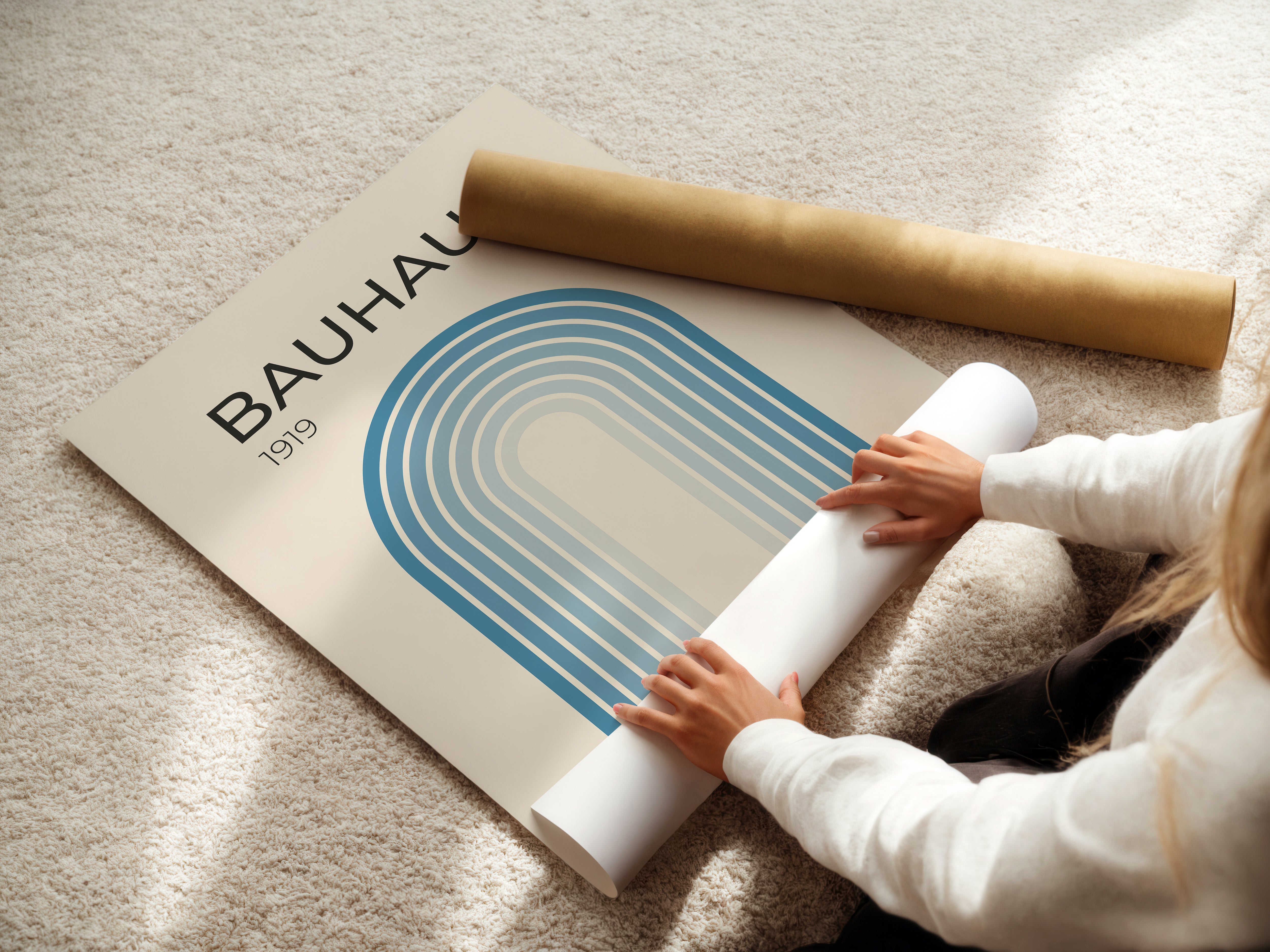 Person rolling out a Bauhaus art print with blue gradient design, showcasing modern design aesthetics.