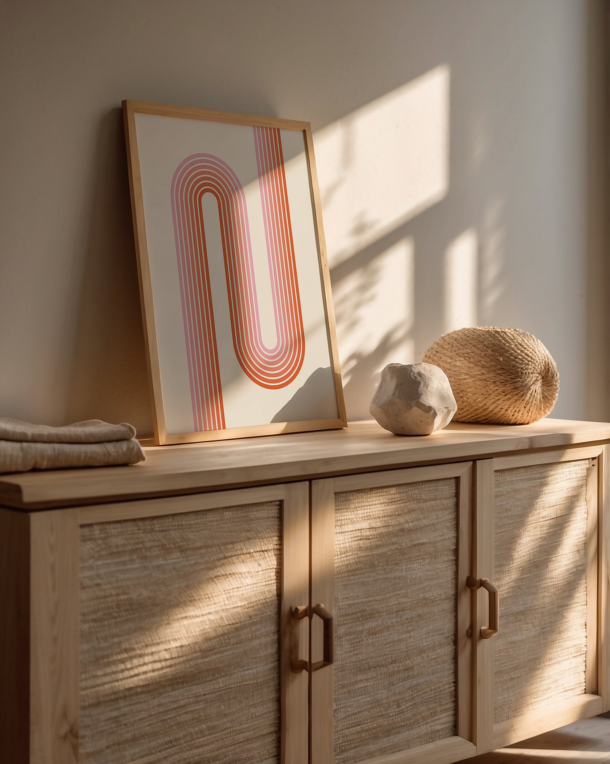 Sunset Stripes wall art print showcasing Bauhaus design with warm coral and blush lines in a modern interior.