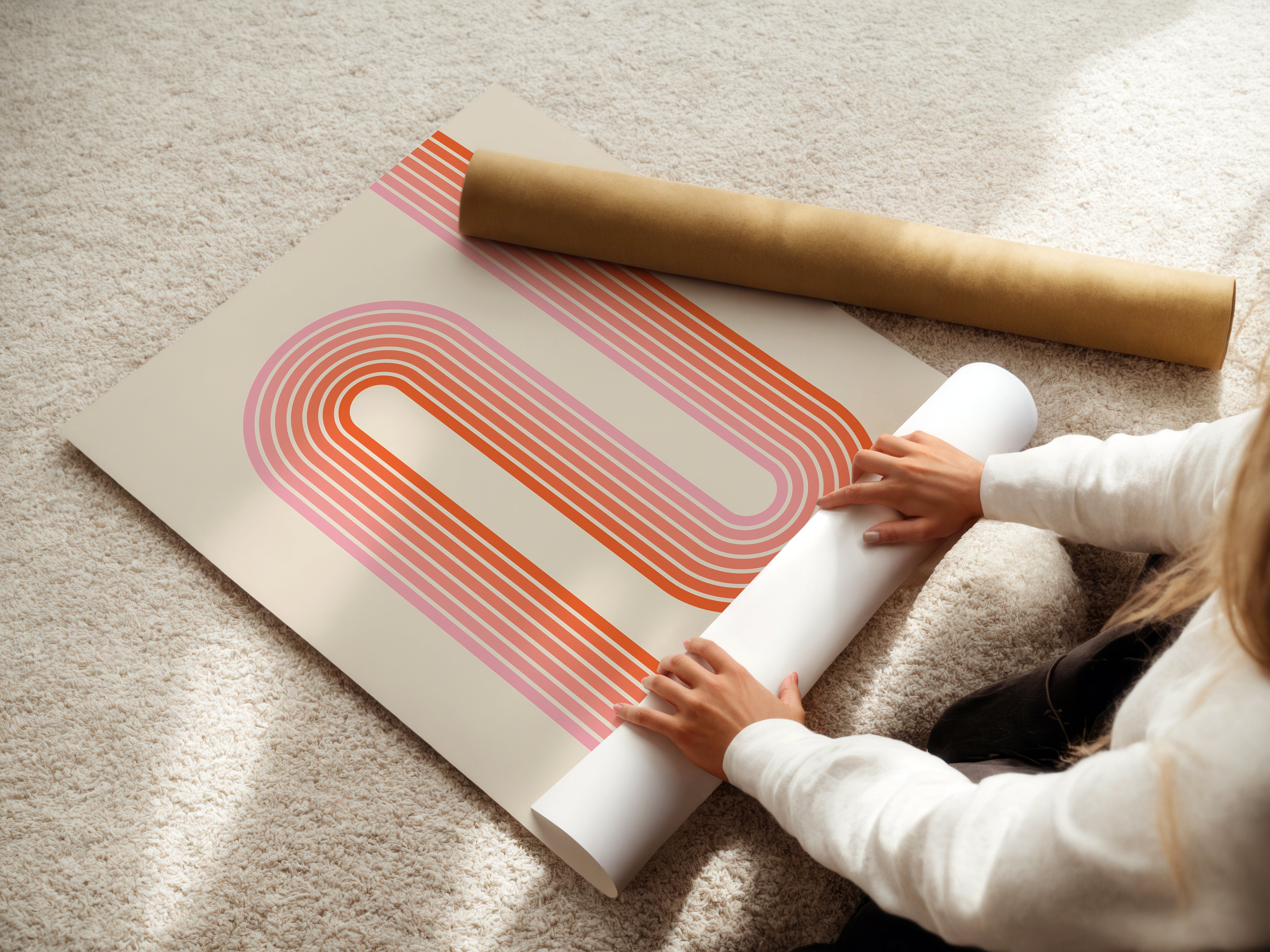 Person laying out the Sunset Stripes wall art print featuring warm coral and blush Bauhaus-inspired design.