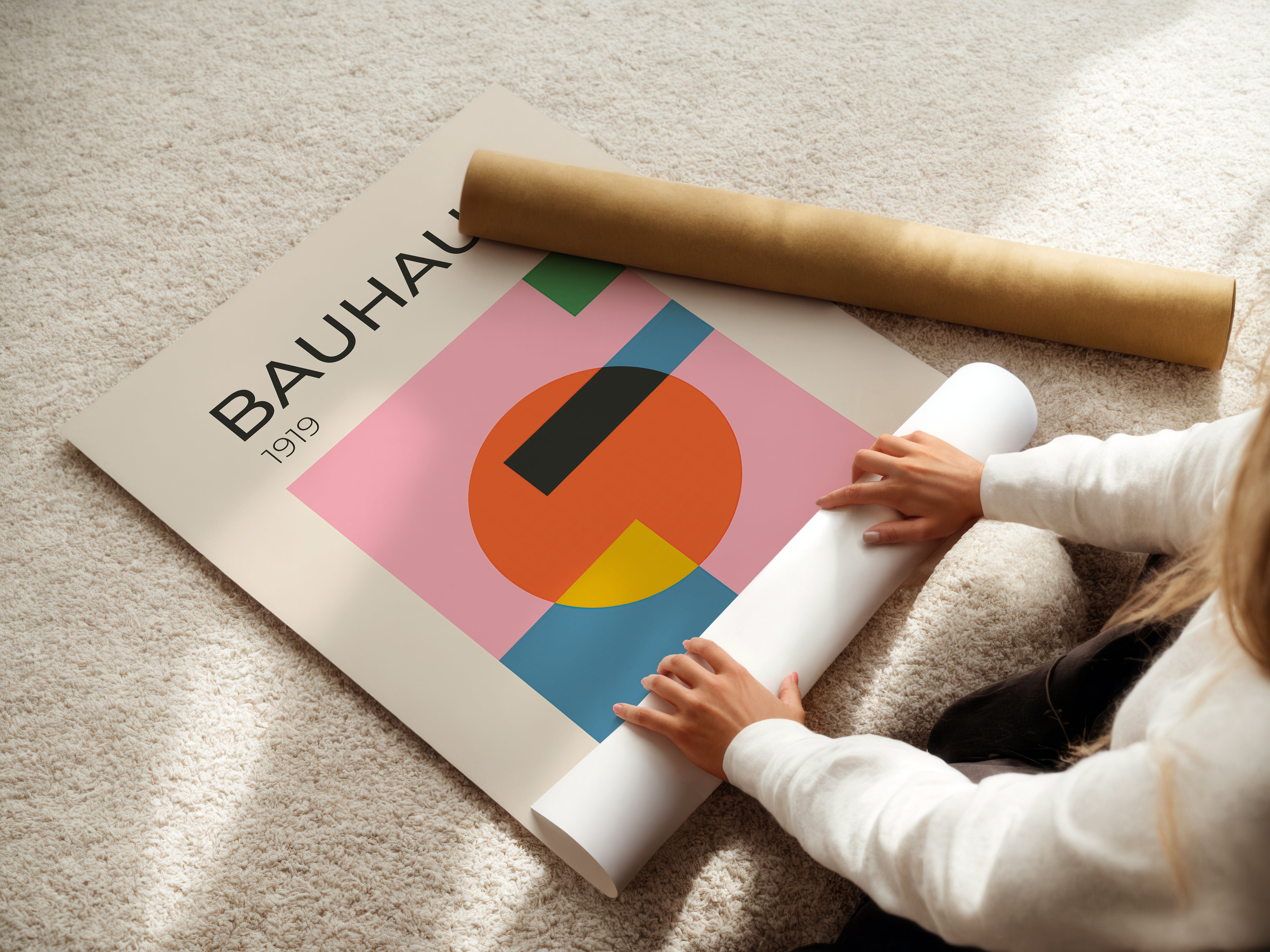 Person unrolling a Bauhaus-inspired art print featuring geometric shapes and vibrant colors.