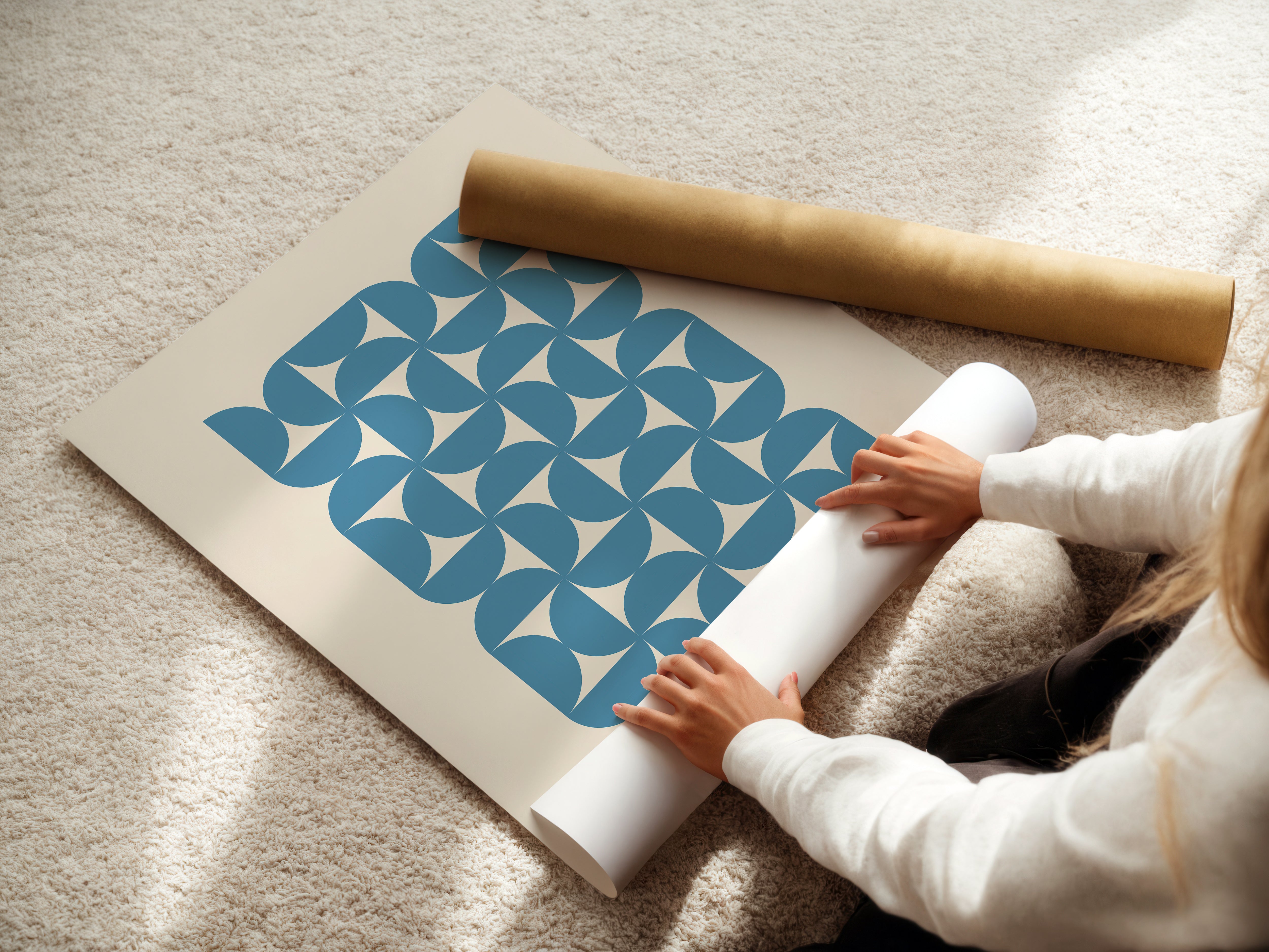 Person unrolling a Bauhaus Waves art print featuring blue geometric semicircles on a neutral background.
