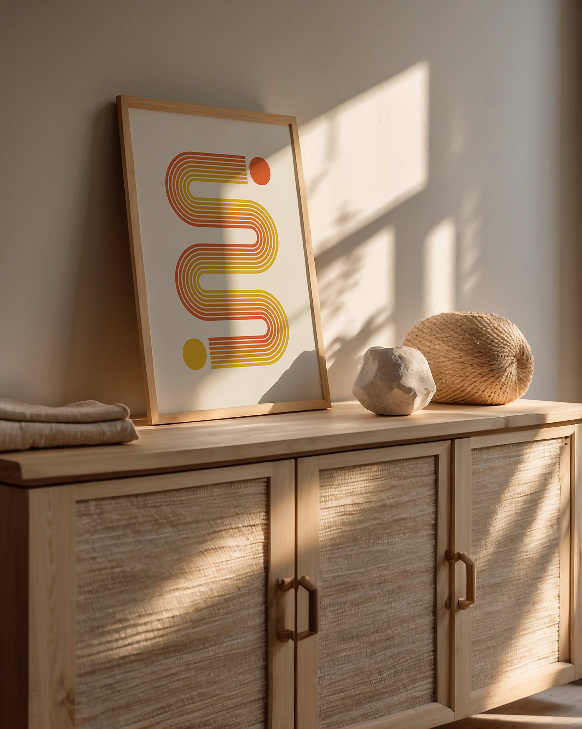Bauhaus-inspired abstract art print with sunset-toned lines and vivid circles in warm interior setting.