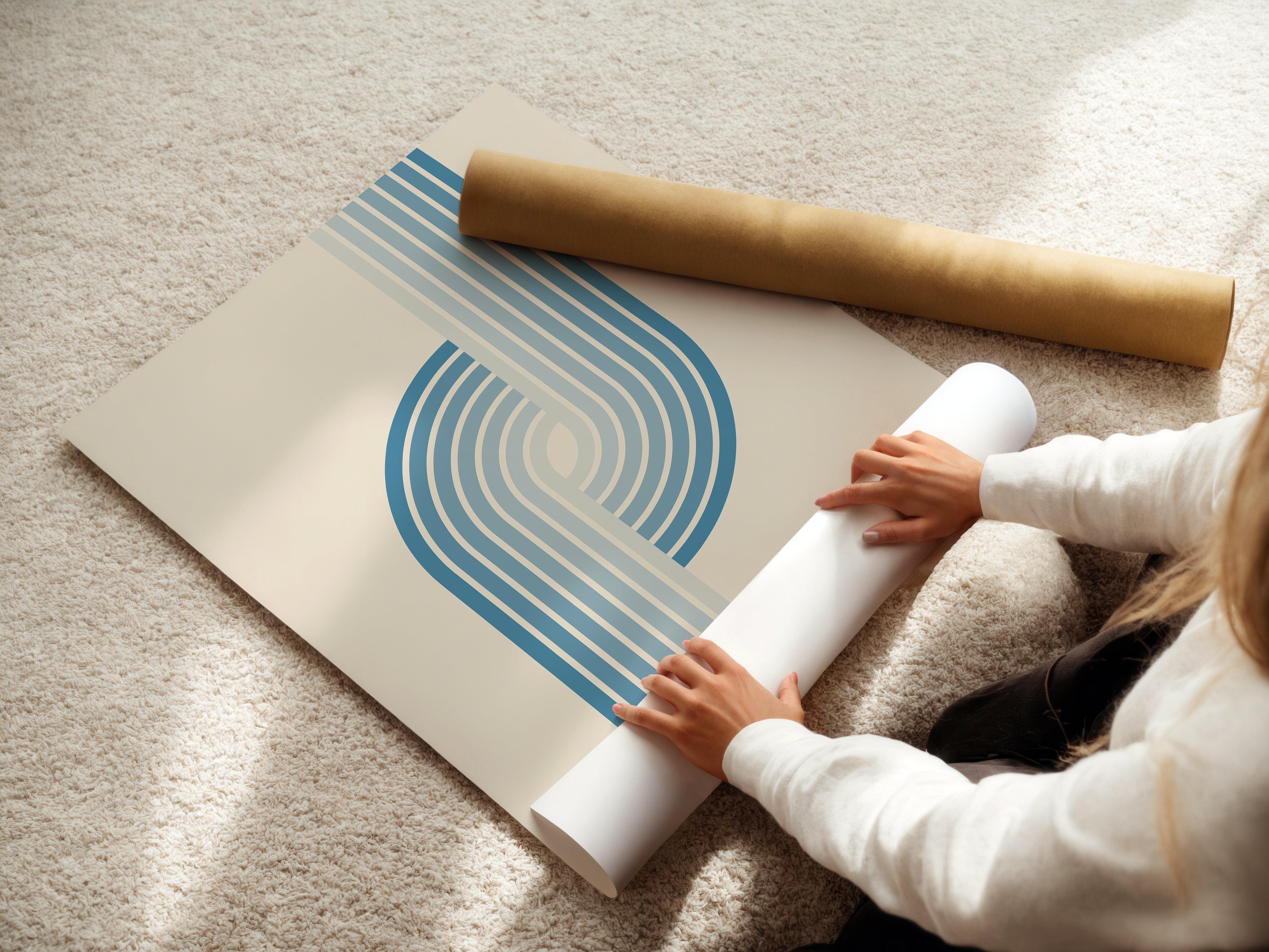 Person unrolling Arctic Current Bauhaus wall art print with blue gradient stripes on a light background.