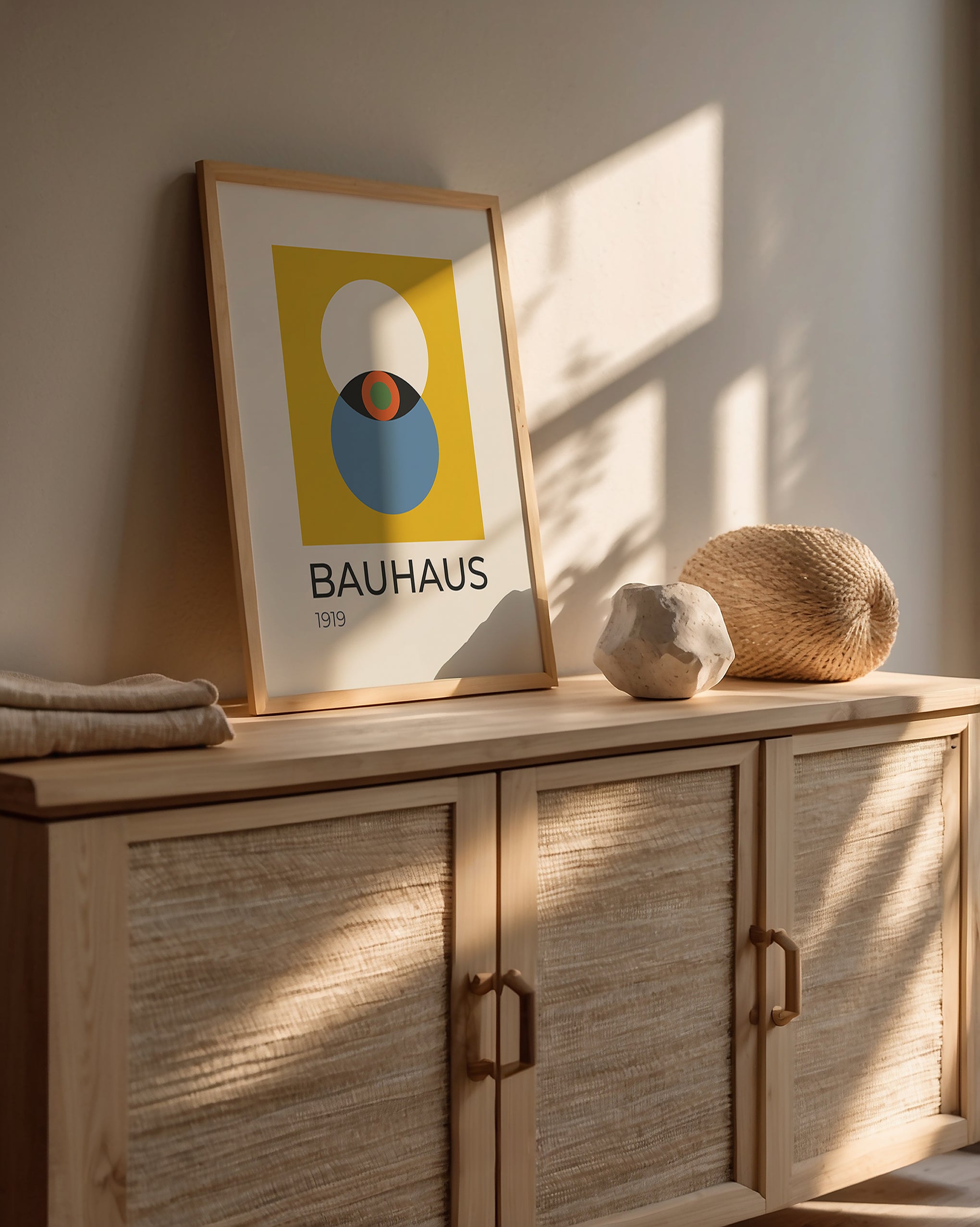 Bauhaus wall art print featuring an abstract eye design in bold colors, displayed on a modern wood cabinet.
