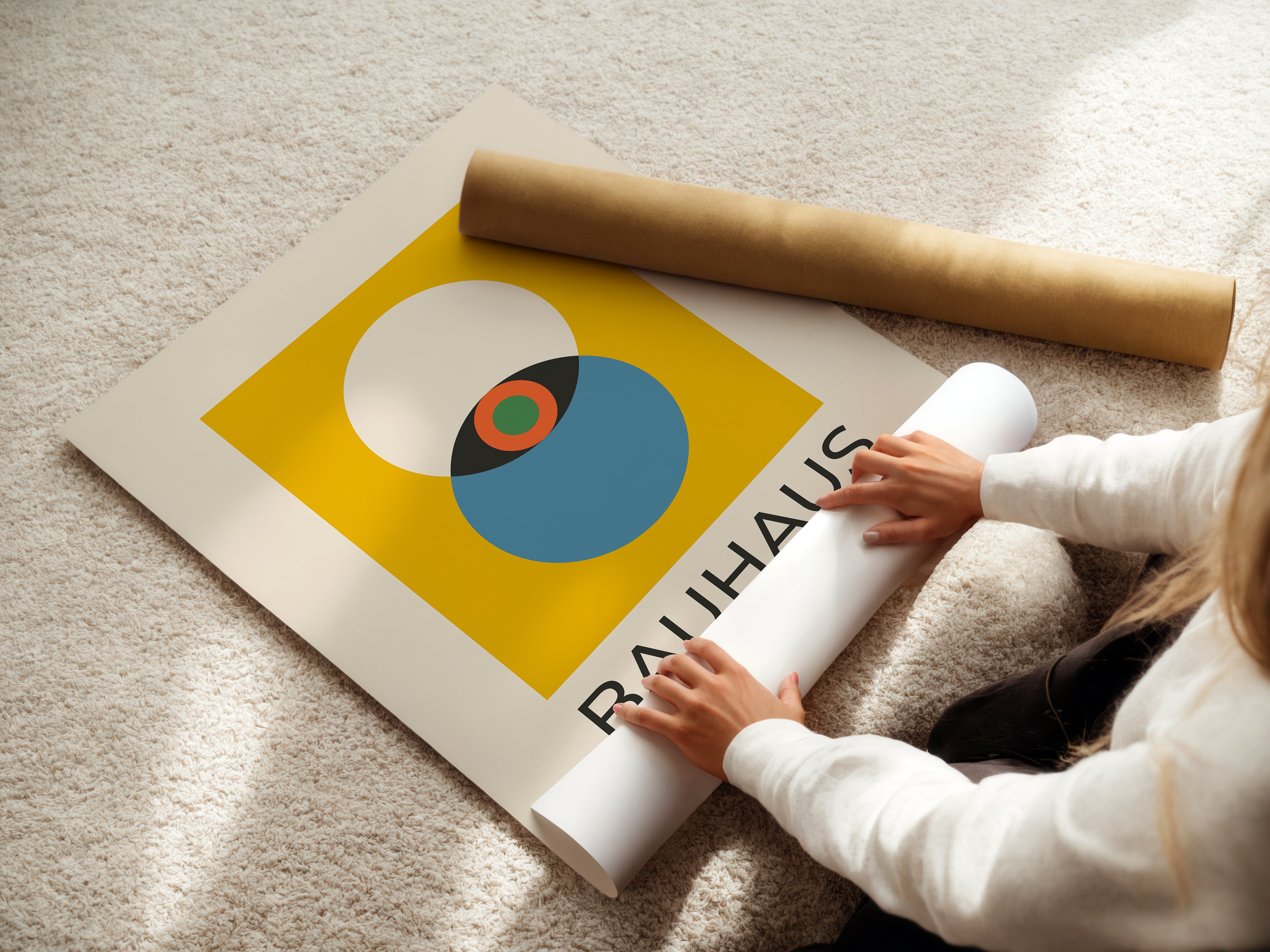Modern Eye Bauhaus wall art print on the floor with a person unrolling it, showcasing bold colors and minimalist design.