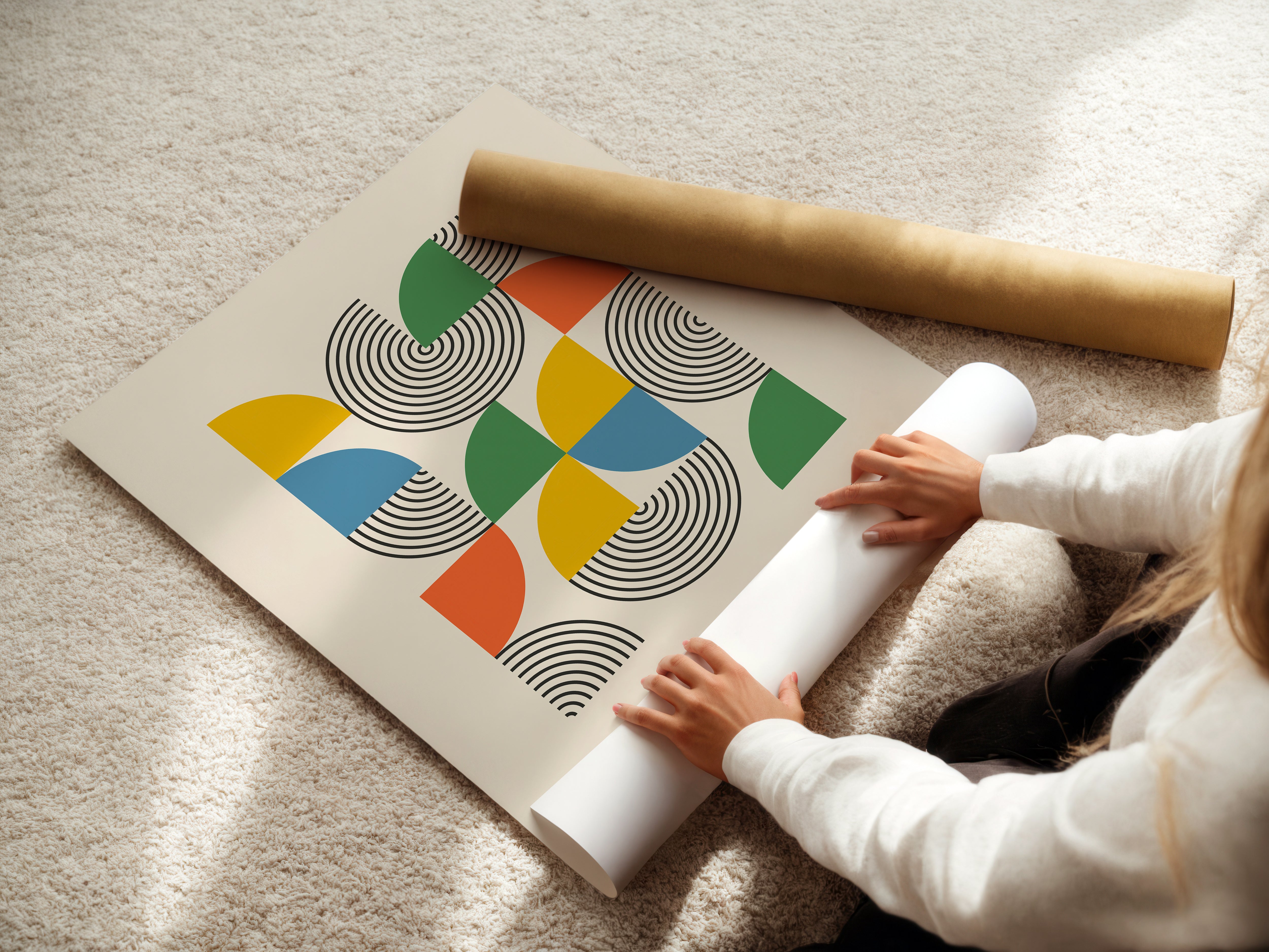 Person unrolling a Bauhaus modern art print, featuring geometric shapes and bold colors like mustard yellow and sky blue.