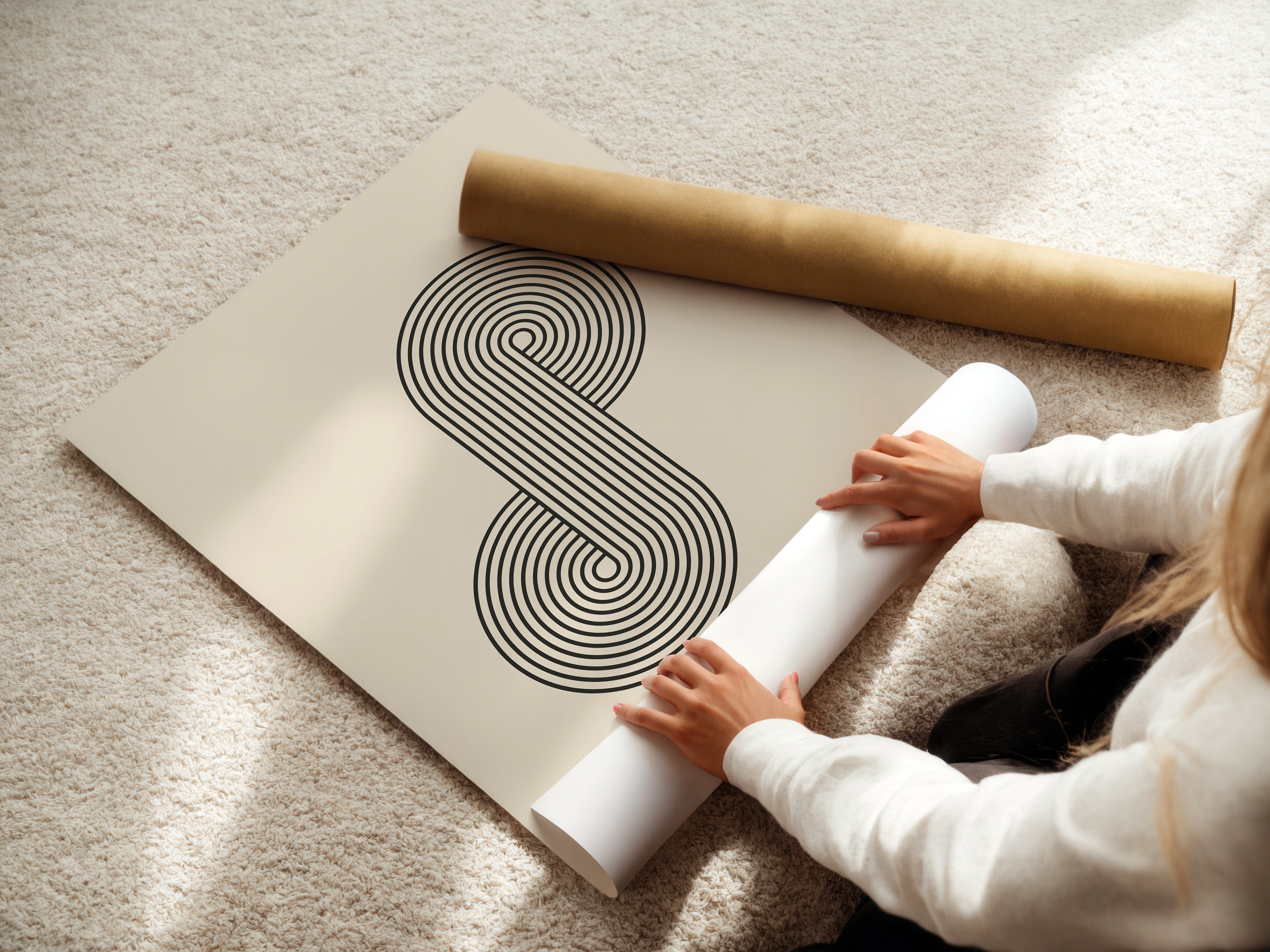 Person unrolling Bauhaus-inspired Infinity Loop wall art print with concentric lines on a neutral background.