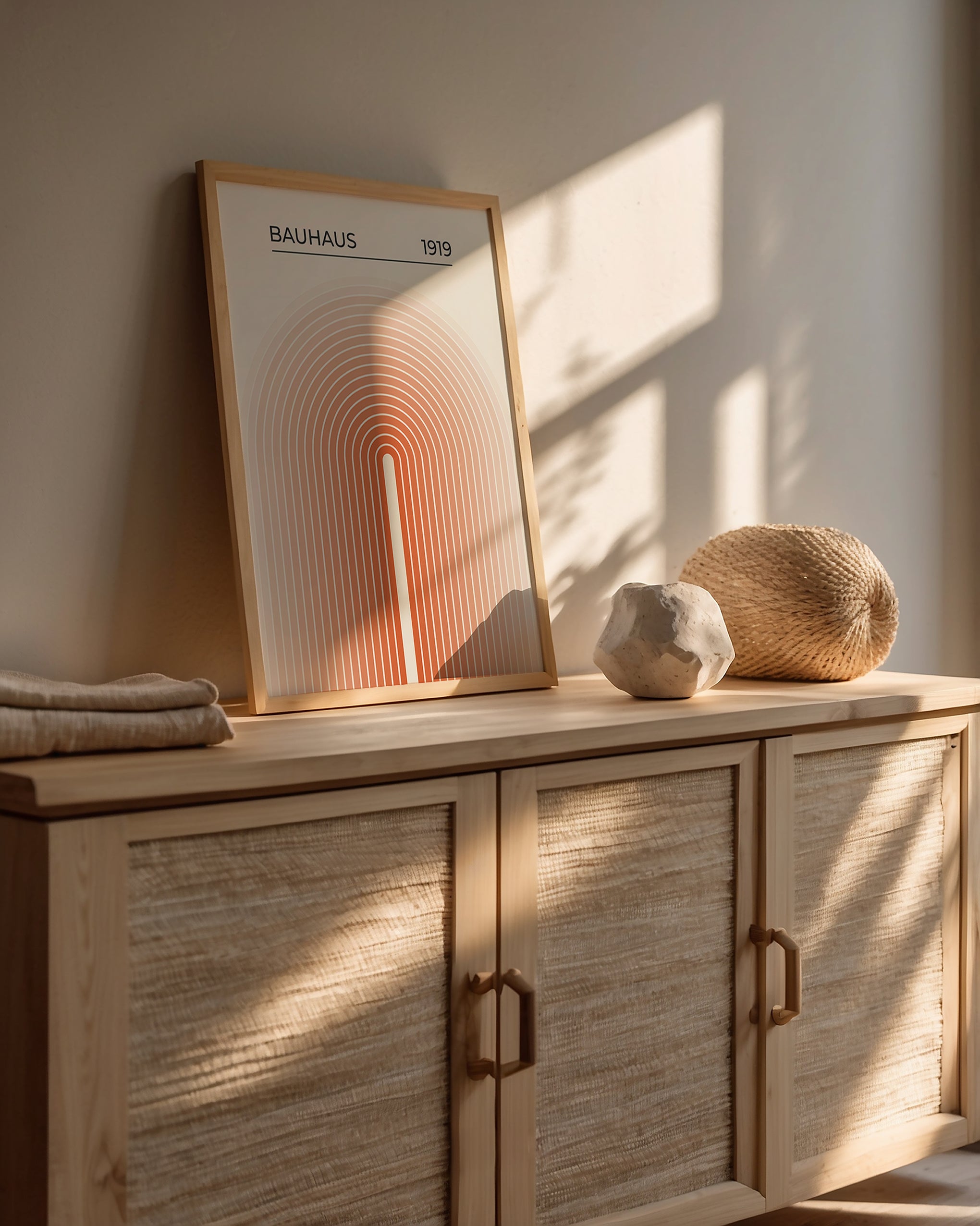Bauhaus wall art print 'Sun Gateway' featuring concentric arches in orange and peach tones, styled in a modern home interior.