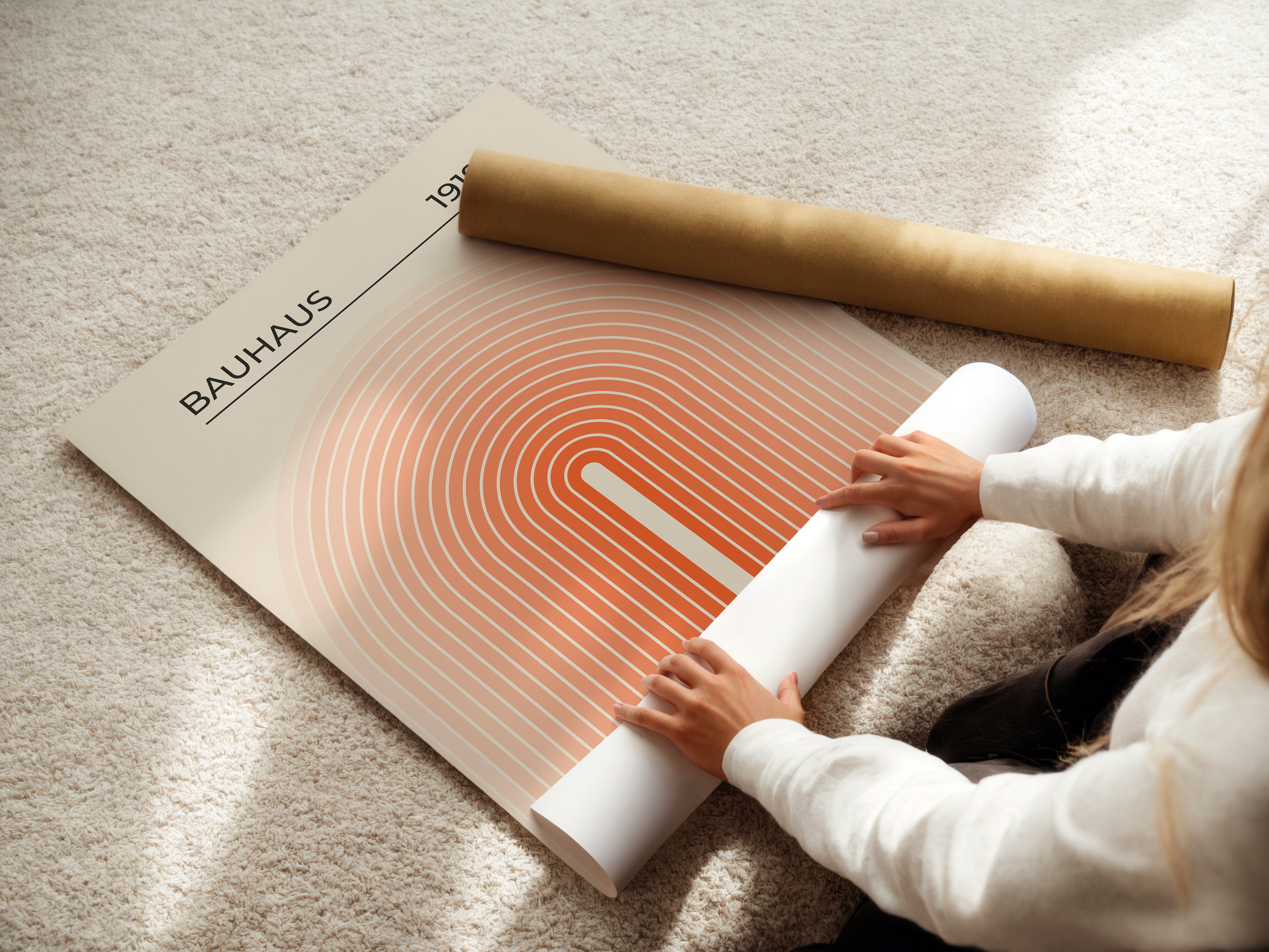 Person unrolling a Bauhaus wall art print with concentric arches in warm colors, showcasing modern art design.