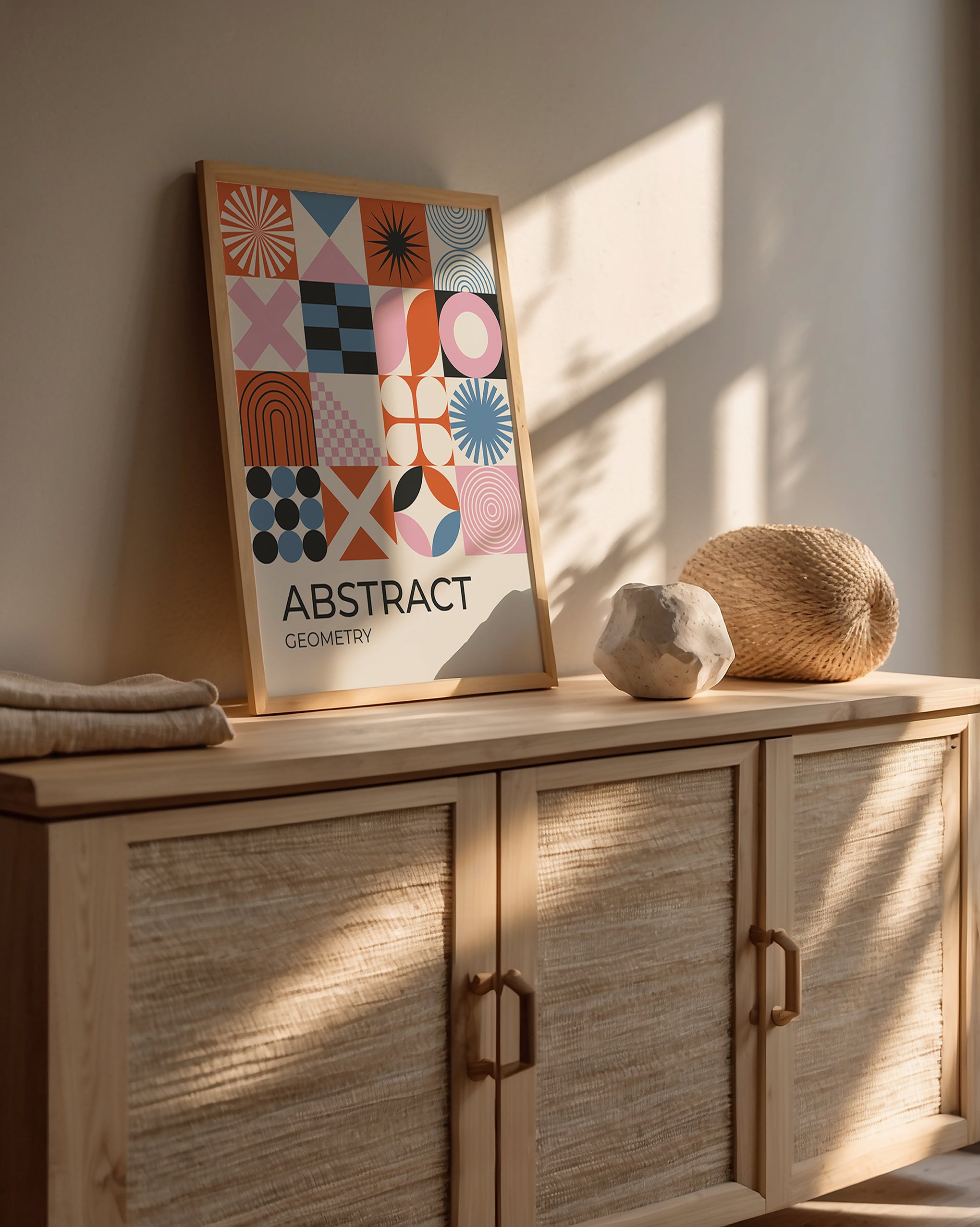 Bauhaus-inspired art print featuring geometric shapes in terracotta, blush, black, and blue on a wooden console.