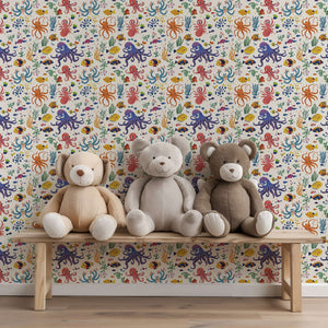 Colorful Reef Buddies wallpaper with octopus and fish in a nursery playroom, featuring plush teddy bears on a bench.