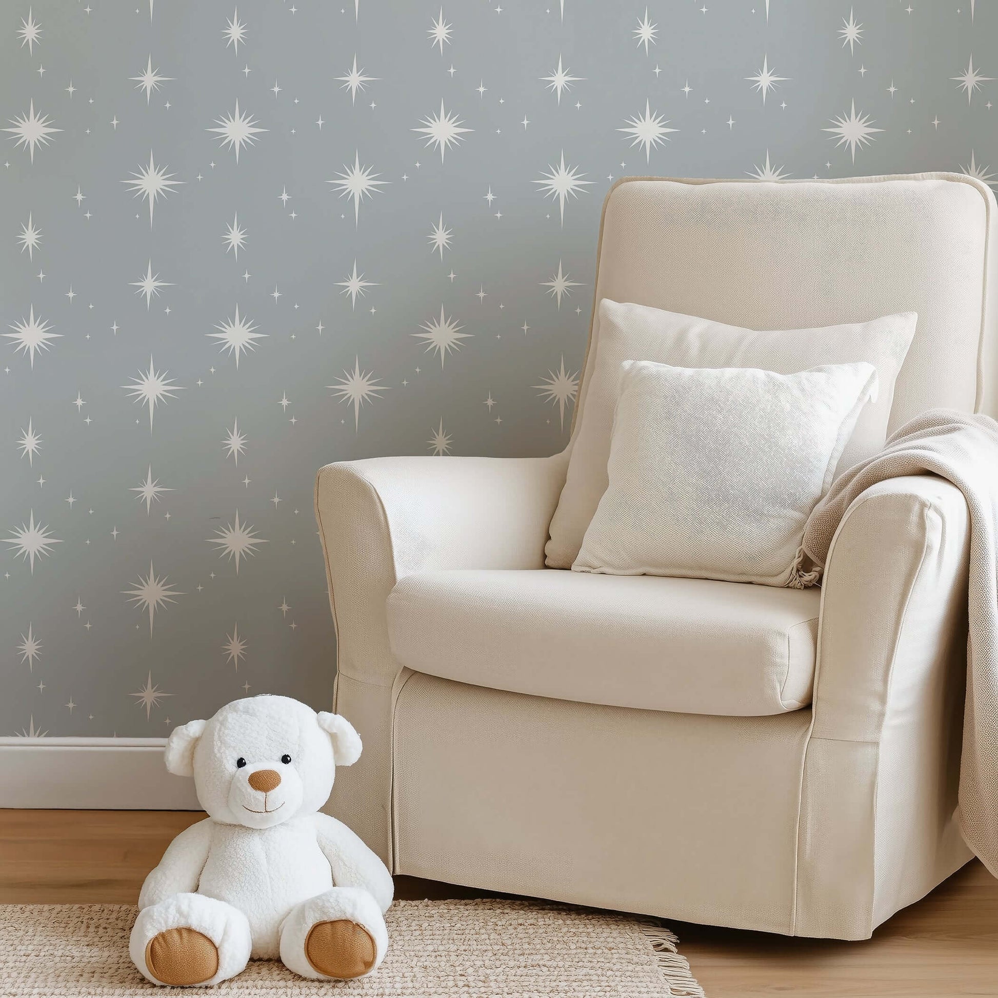 Cozy nursery with gray starry wallpaper, cream chair, and teddy bear enhancing serene playroom vibe.