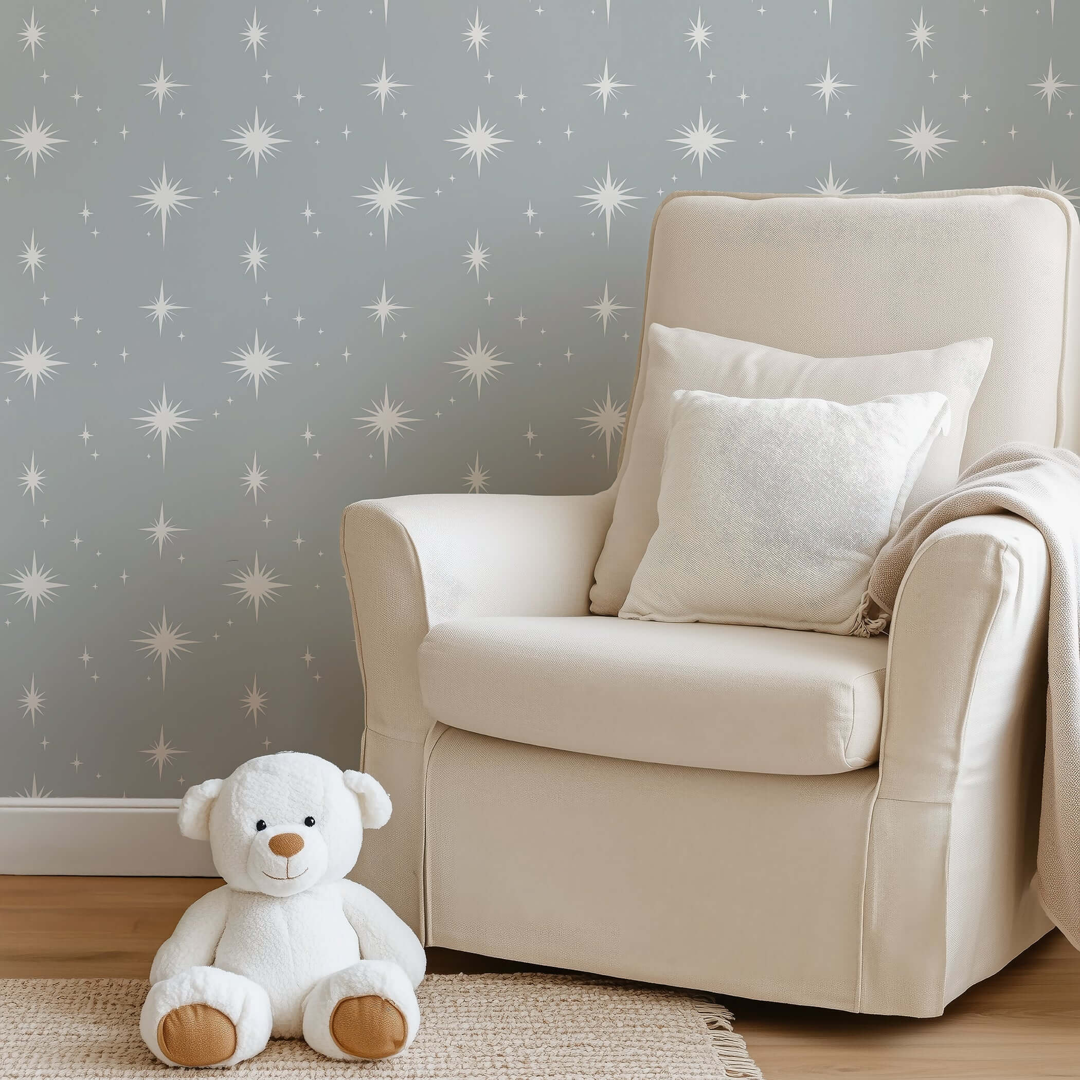 Cozy nursery with gray starry wallpaper, cream chair, and teddy bear enhancing serene playroom vibe.