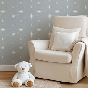 Cozy nursery with gray starry wallpaper, cream chair, and teddy bear enhancing serene playroom vibe.