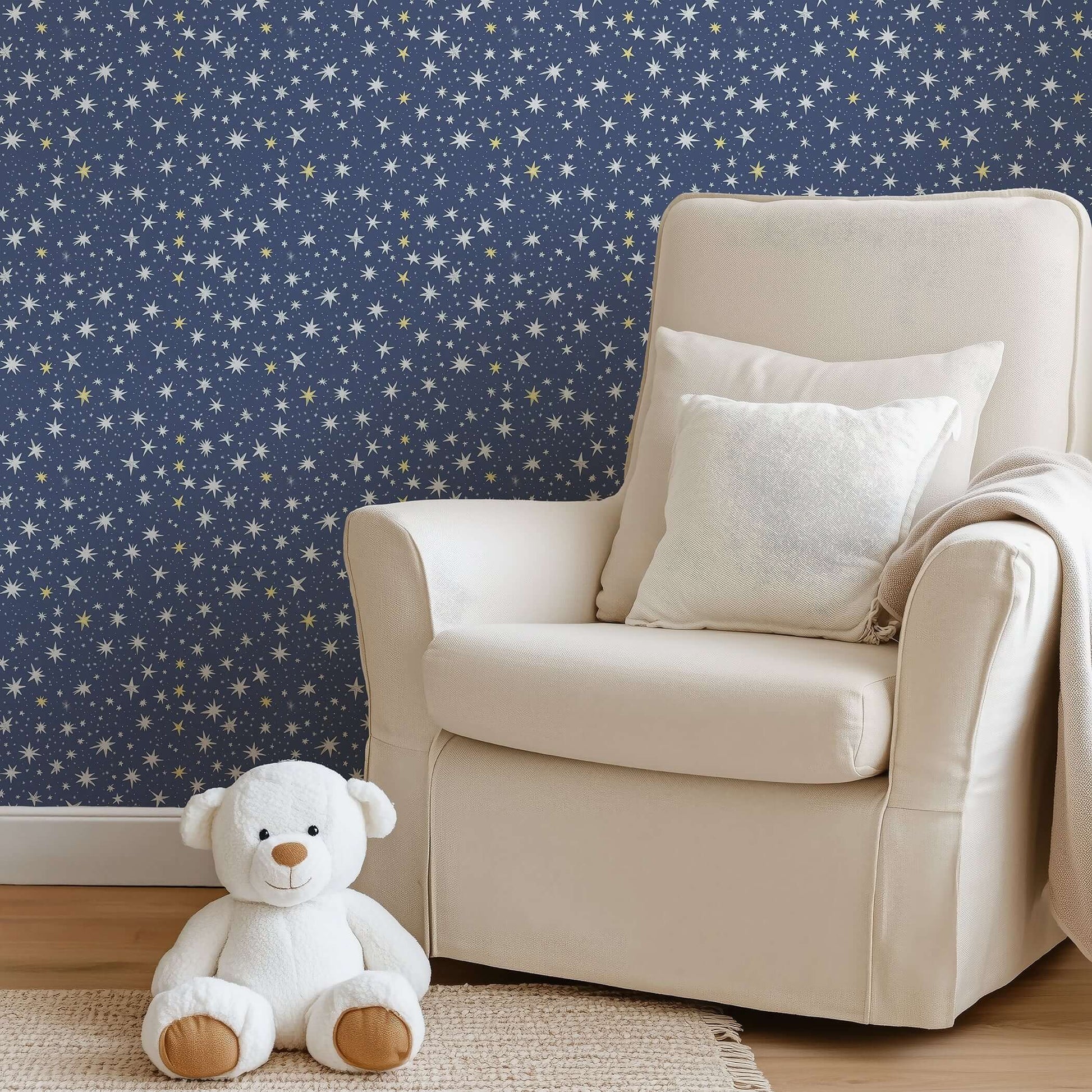 Nursery adorned with Twinkle Twinkle Little Star wallpaper featuring white and gold stars on navy, with a teddy bear and comfy chair.