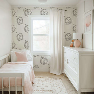 Nursery featuring Lambs Meadow Dream wallpaper with baby lambs in floral wreaths, perfect for children and playrooms, in cream tones.