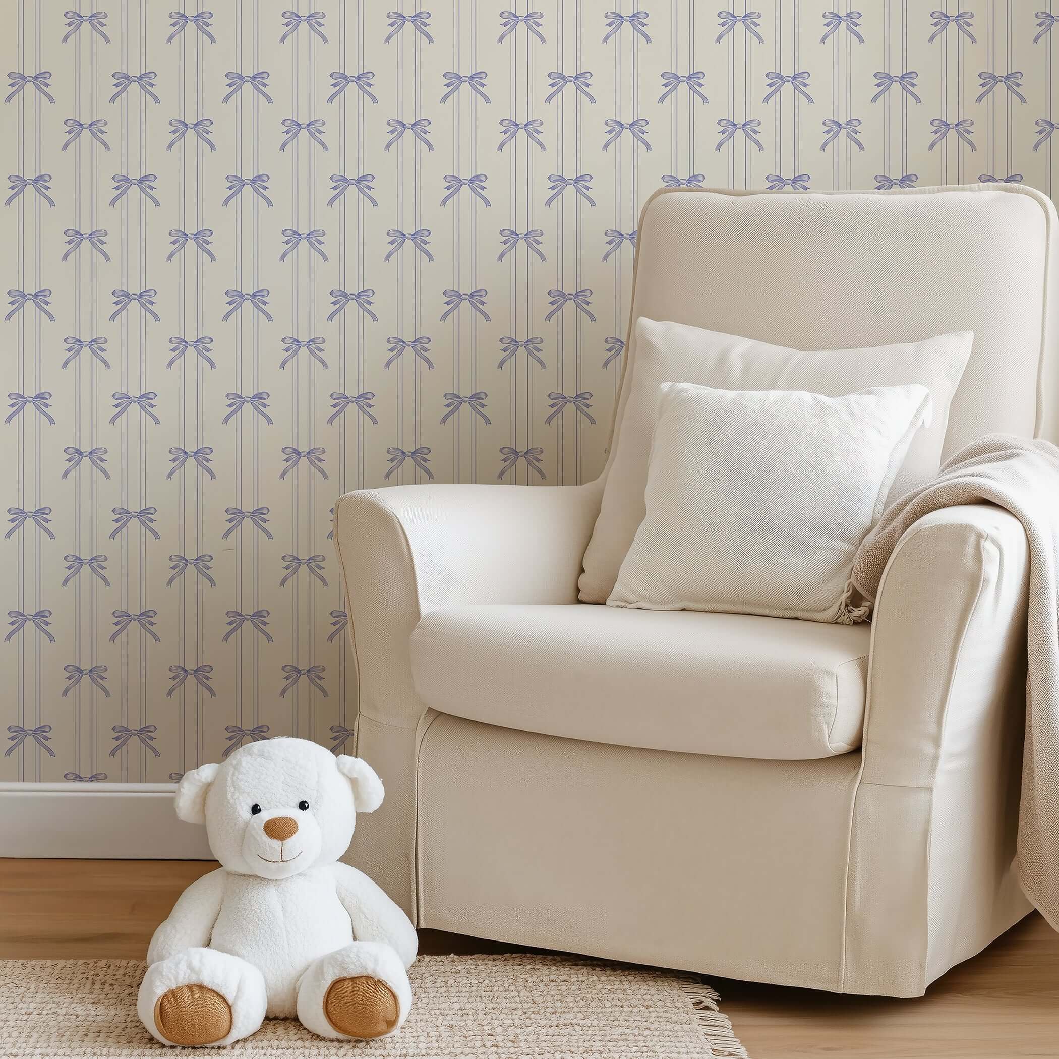 Soft cream chair in nursery with teddy bear and Lavender Ribbons wallpaper featuring hand-drawn bows for a cottagecore look.