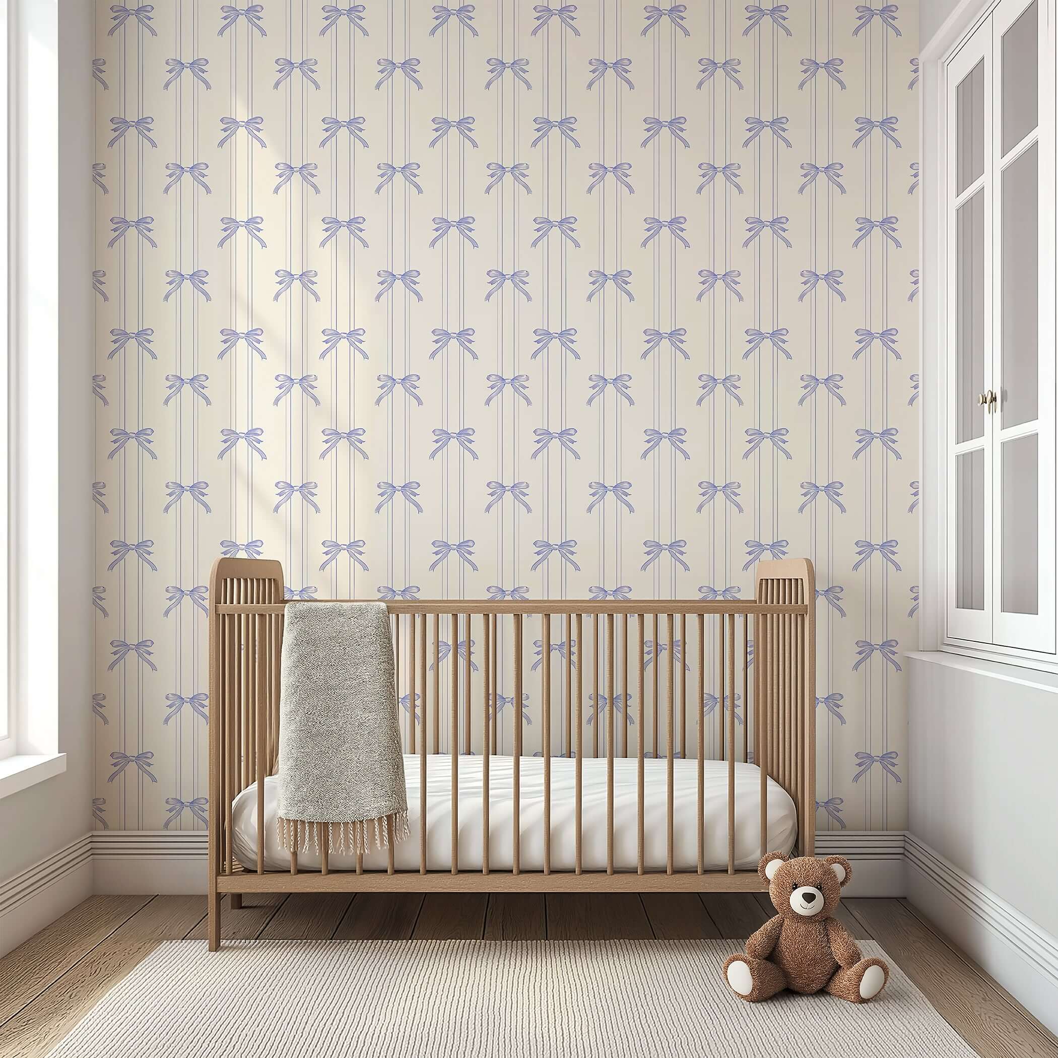 Lavender Ribbons wallpaper with hand-drawn bows in a nursery setting, featuring a wooden crib and teddy bear. Perfect for baby rooms.