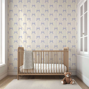 Lavender Ribbons wallpaper with hand-drawn bows in a nursery setting, featuring a wooden crib and teddy bear. Perfect for baby rooms.