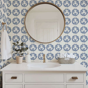 The Majestic Laurel Rings wallpaper featuring navy laurel wreaths on ivory, enhancing a bathroom with botanical luxury.