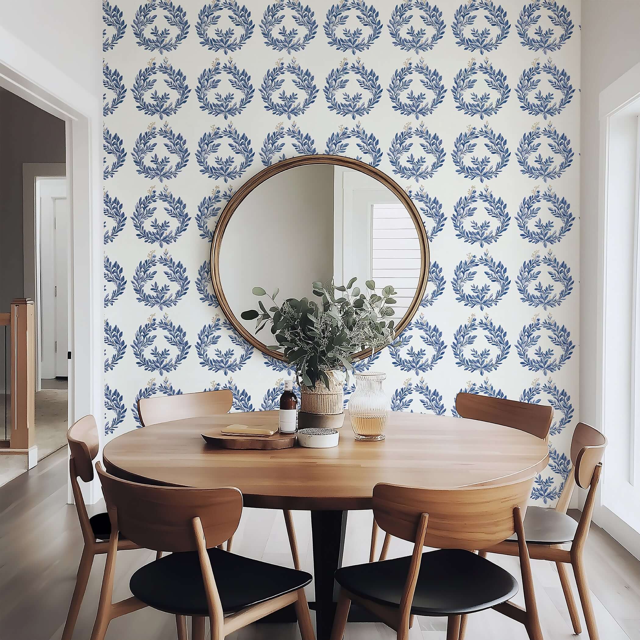 Navy laurel wreath wallpaper in dining room with wooden table, creating elegant botanical ambiance.