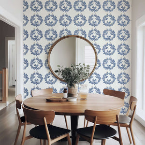 Navy laurel wreath wallpaper in dining room with wooden table, creating elegant botanical ambiance.