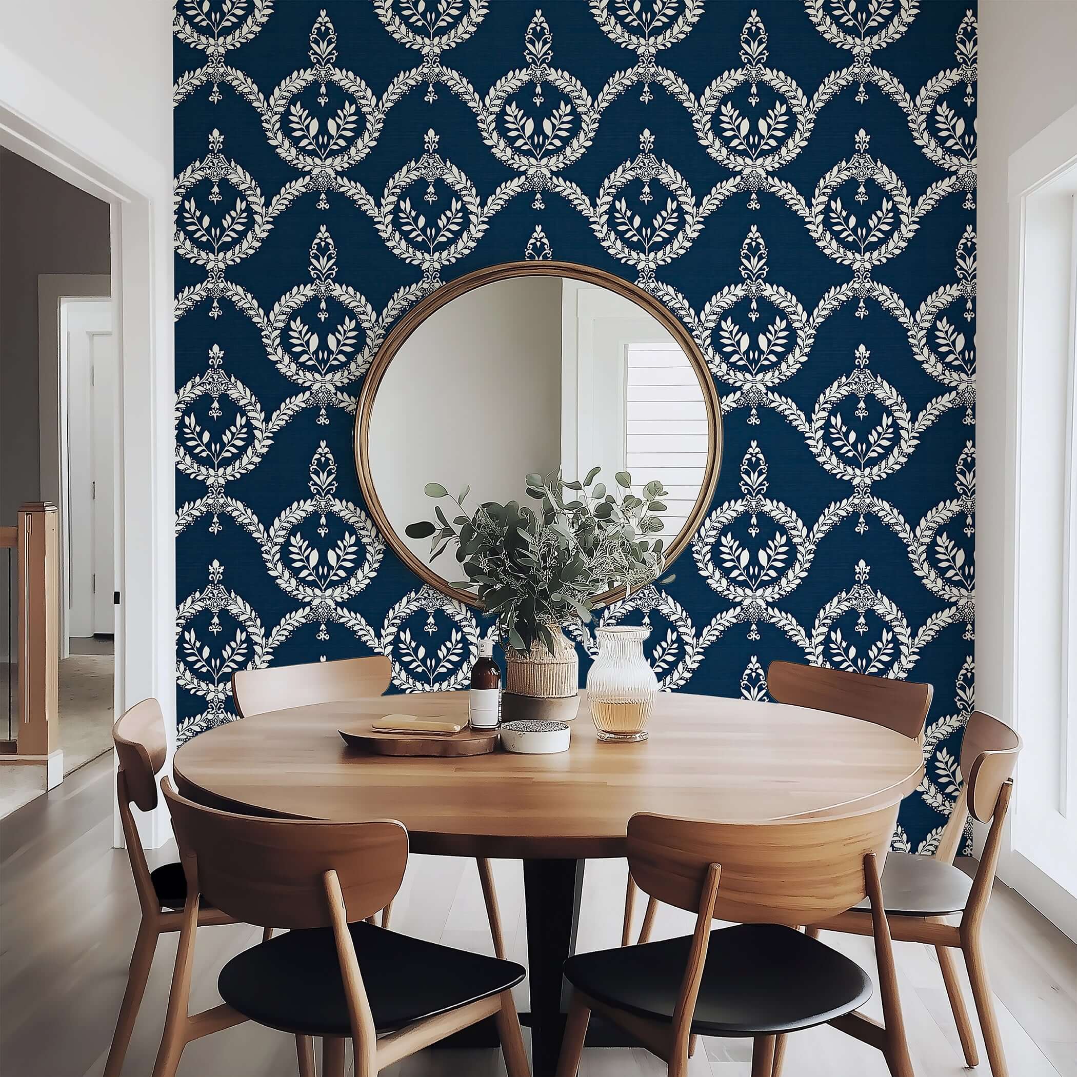 Navy wallpaper with ivory laurel wreath pattern behind a dining table, creating a vintage crest look for elegant interiors.