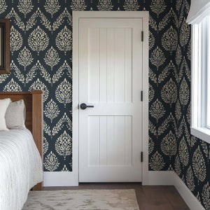 Heritage Flora wallpaper with ivory botanical pattern on charcoal, featuring laurels, adding elegance to a bedroom with white door.