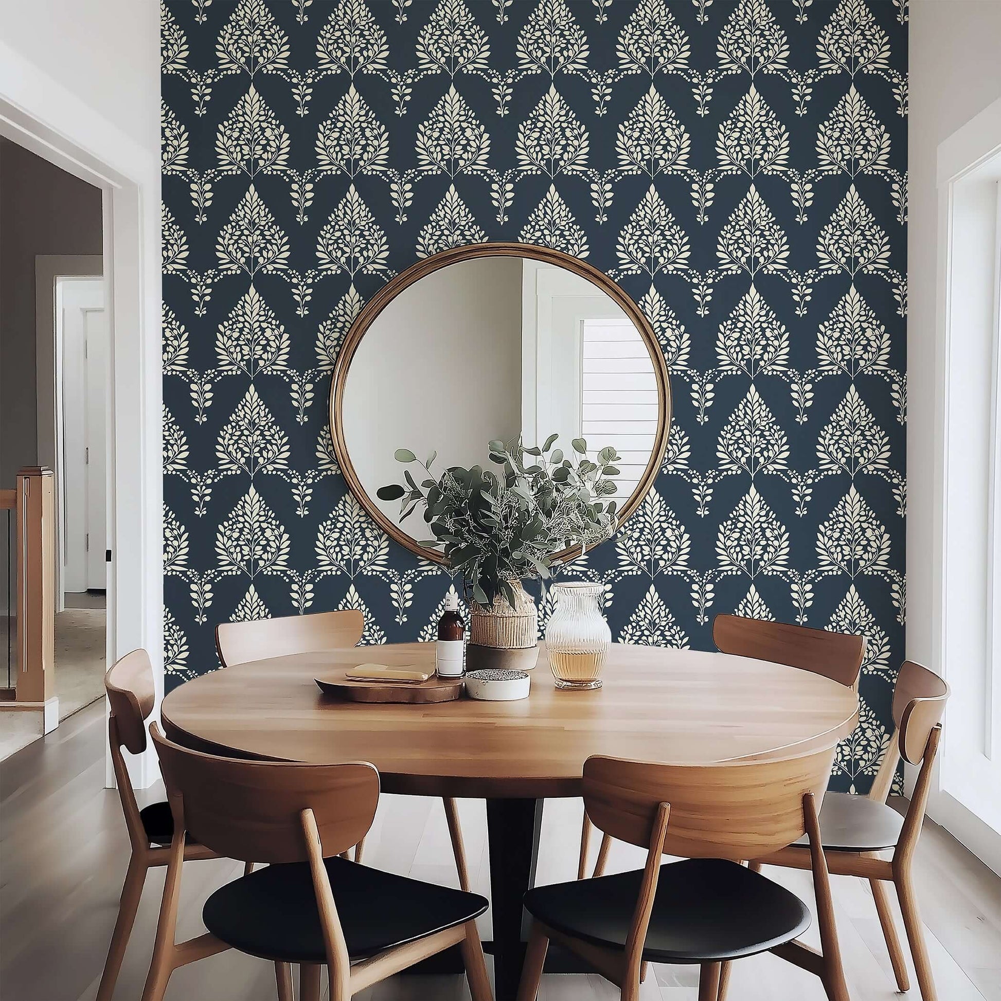 Dining area with Noir Bloom floral laurel wallpaper in deep charcoal, featuring a round wooden table and chairs.