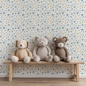 Mid-century modern wallpaper with gold and blue snowflakes, perfect for holiday decoration, behind plush toys on a wooden bench.