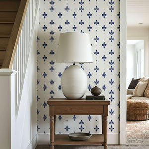 Elegant room featuring Navy Luxe Fleur wallpaper with navy fleur-de-lis pattern, accented by a classic lamp on a wooden table.