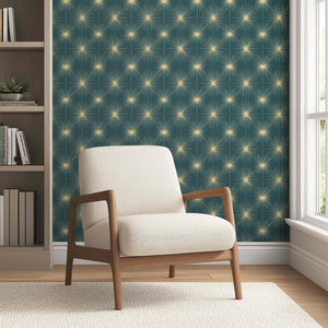 Mid-Century Modern room with Celestial Gold Sparkle wallpaper, featuring golden starbursts on teal-blue, and a retro beige chair.