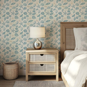 Coastal wallpaper featuring hand-drawn seashells and starfish in ocean blues, enhancing a serene bedroom setting with marine charm.