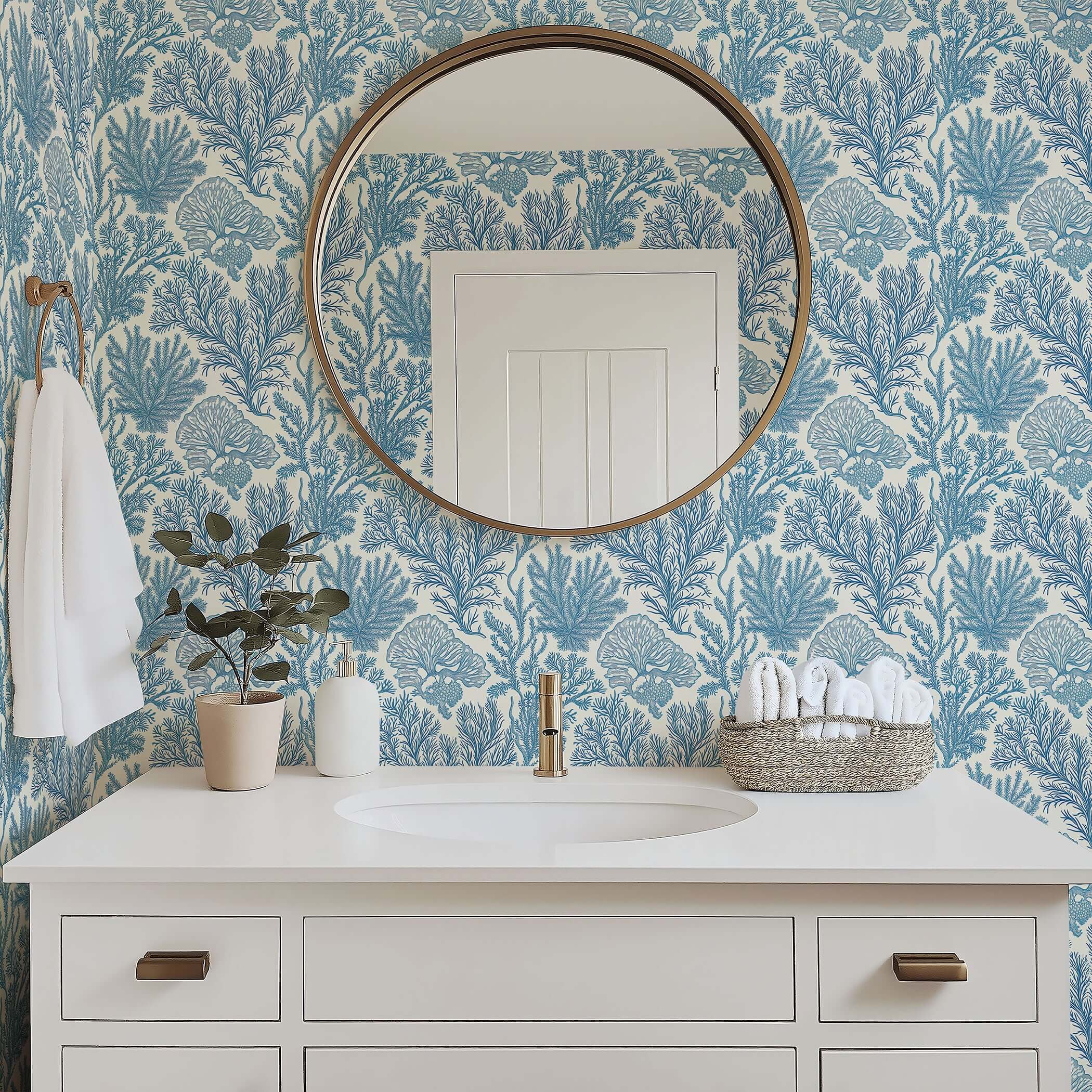 Bathroom with Maritime Meadow wallpaper featuring coastal blue ocean plant motifs, coral design, and elegant mirror above white vanity.