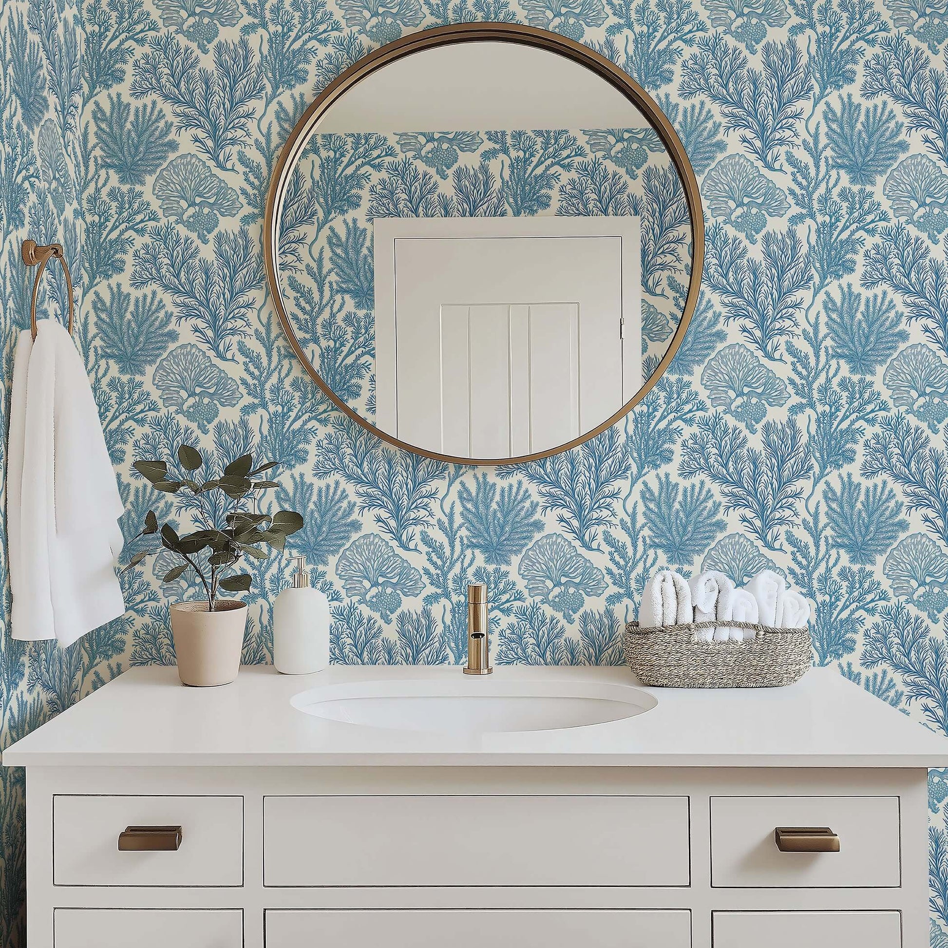 Bathroom with Maritime Meadow wallpaper featuring coastal blue ocean plant motifs, coral design, and elegant mirror above white vanity.