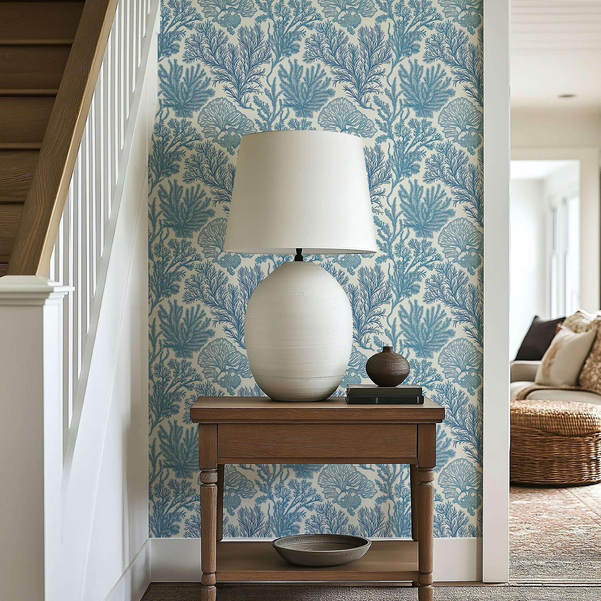Lamp on wood table against coastal blue 'Maritime Meadow' wallpaper with coral and marine plant designs, creating an oceanic ambiance.