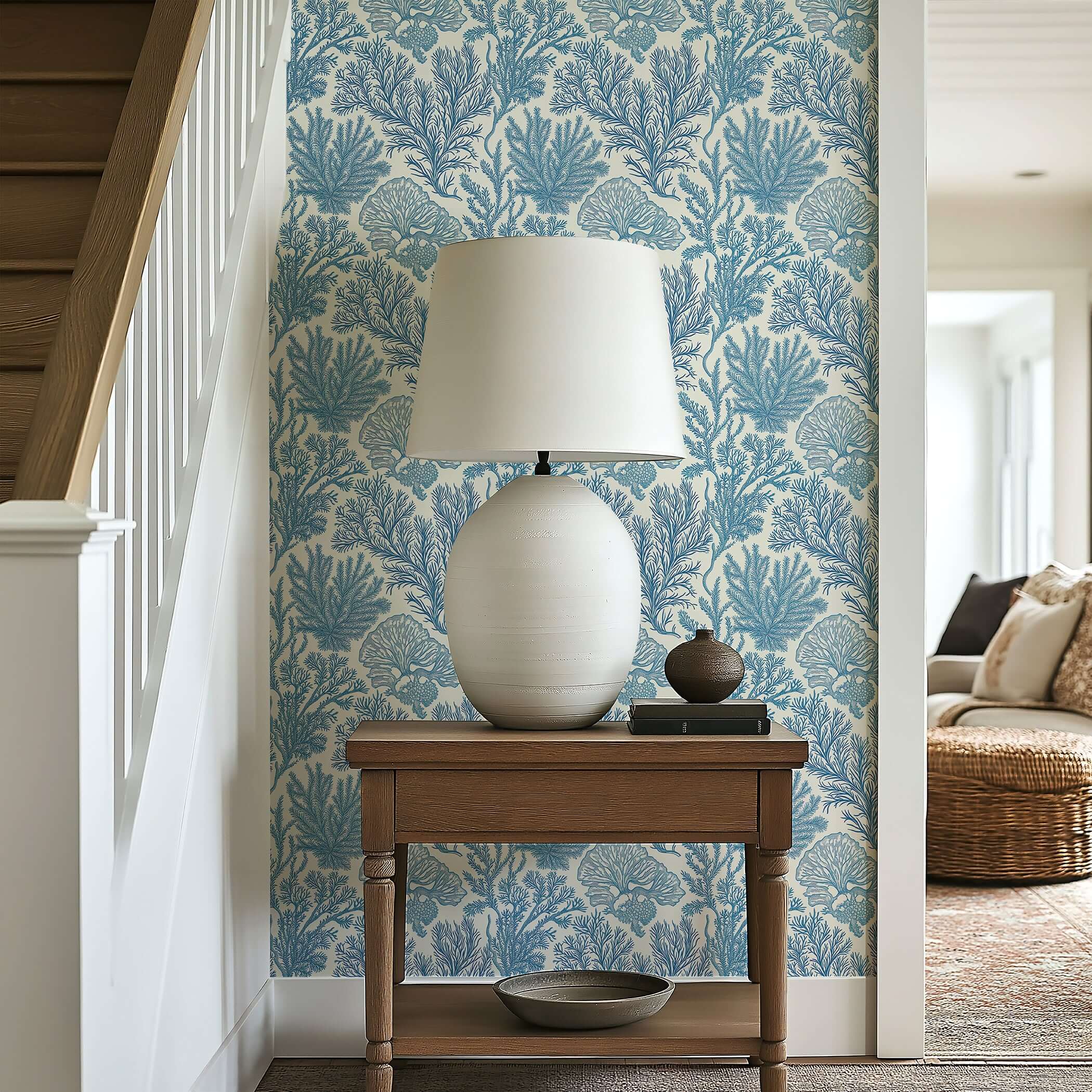 Lamp on wood table against coastal blue 'Maritime Meadow' wallpaper with coral and marine plant designs, creating an oceanic ambiance.
