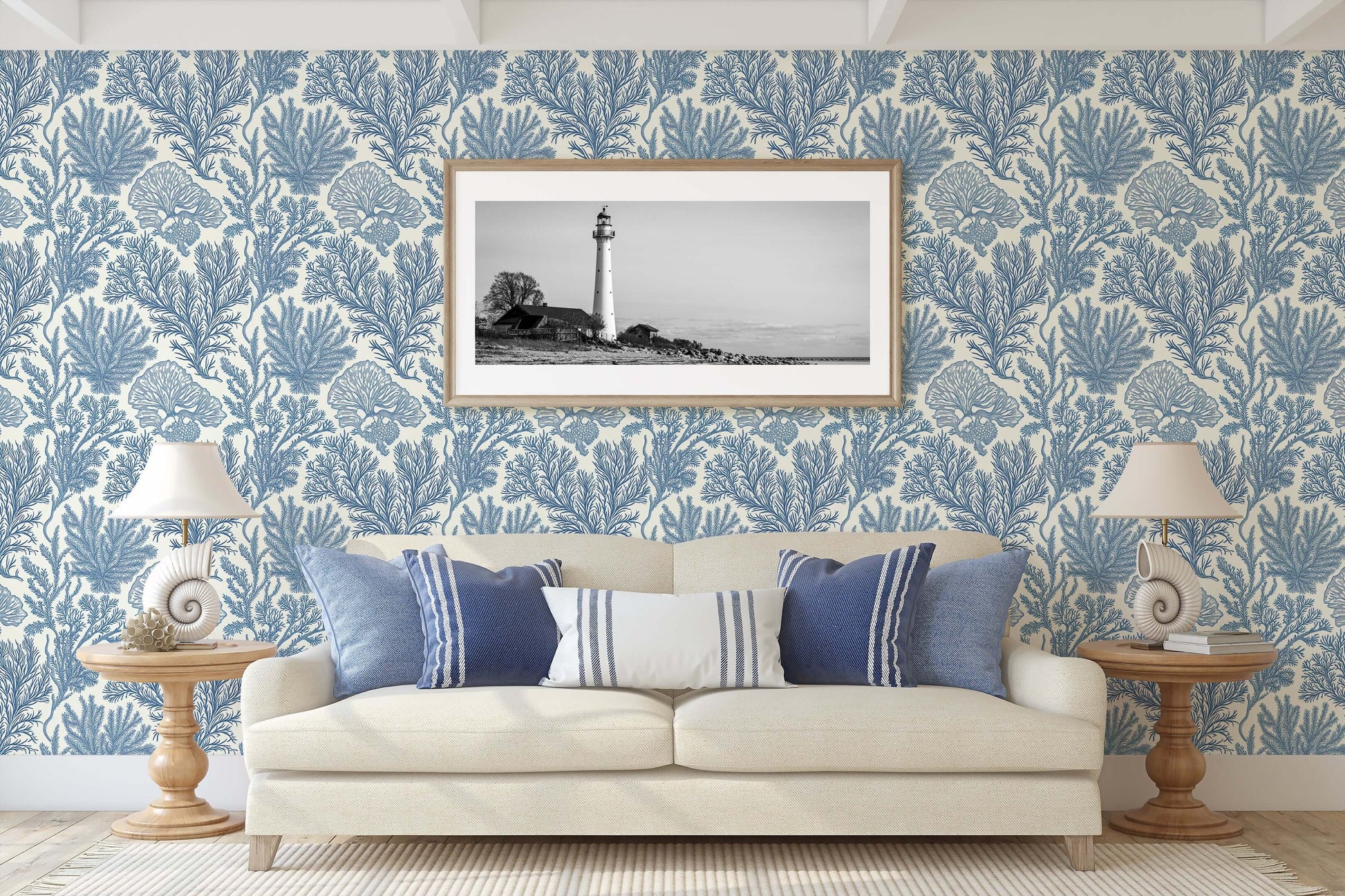 Coastal living room with Maritime Meadow wallpaper in ocean blue, featuring marine botanical prints, coral designs, and lighthouse artwork.