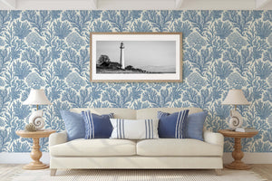 Coastal living room with Maritime Meadow wallpaper in ocean blue, featuring marine botanical prints, coral designs, and lighthouse artwork.