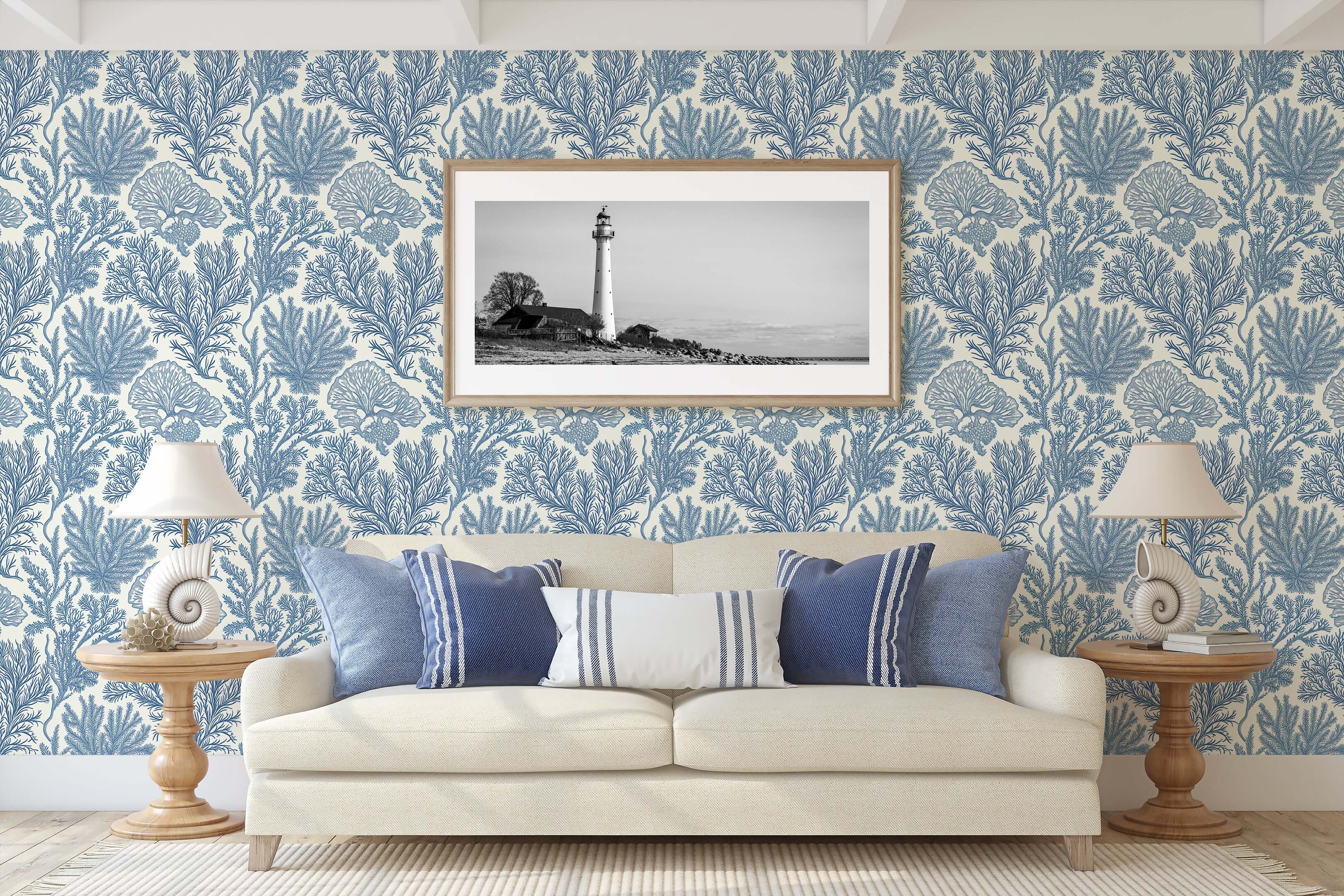Coastal living room with Maritime Meadow wallpaper in ocean blue, featuring marine botanical prints, coral designs, and lighthouse artwork.