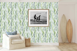 Kelp Cascade ocean-themed coastal wallpaper with green strands adding marine elegance to living room decor with framed photo and surfboards.