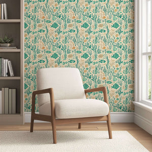 Mid-century modern chair against a coastal wallpaper featuring fish, coral, and seaweed in teal and sandy hues for a serene atmosphere.
